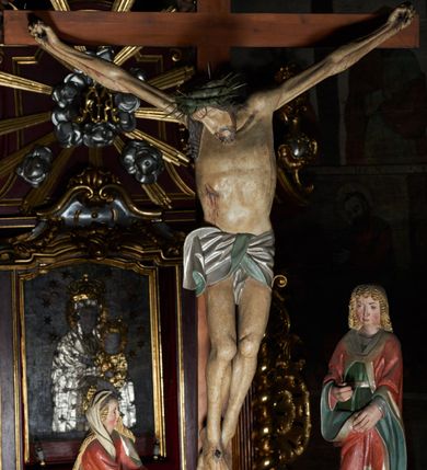 Zdjęcie nr 4: Krucyfiks w typie Cristo morte. Chrystus przybity do krzyża trzema gwoździami, sylwetka w delikatnym zwisie, z głową przechyloną na prawe ramię, o silnie podkreślonej anatomii ciała, z zaznaczonymi śladami męki. Perizonium w formie tkaniny przewiązanej na prawym biodrze. Twarz podłużna, okolona zarostem; włosy długie spływające na prawe ramię w kręcone pukle, na głowie korona cierniowa. Polichromia w odsłoniętych partiach ciała naturalistyczna.