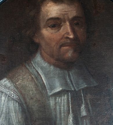 Zdjęcie nr 1: Obraz w kształcie medalionu, przedstawiający popiersie księdza Andrzeja Strzałkowskiego na czarnym tle. Ksiądz zwrócony w trzech czwartych w lewo, ubrany w komżę z koloratką oraz z przewieszoną przez szyję fioletową stułą. Twarz zwrócona delikatnie w lewo, okolona krótkim zarostem, nos pociągły, oczy ciemne ze wzrokiem skierowanym na wprost, wysokie czoło, gęste włosy o średniej długości. Rama drewniana, profilowana, malowana na czarno.
