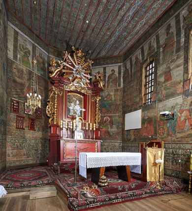 Zdjęcie nr 76: Polichromia ścienna prezbiterium
Polichromia w tej części świątyni podzielona jest na cztery strefy. W pierwszej znajduje się dekoracja ornamentalna, kolejne dwie strefy ukazują sceny z życia Marii i Jezusa, ostatnia strefa ukazuje rząd portretów męskich w strojach z epoki.  W dolnej strefie prezbiterium są umieszczone również trzy krzyże konsekracyjne, wpisane w okrągłe wieńce. Na północnej ścianie prezbiterium w scenach z cyklu maryjnego, od lewej znajdują się: Św. Anna Samotrzeć, Pokłon Trzech Króli, Chrystus Baranek Boży opatrzony banderolą z napisem: „EGO SVM PASTOR BONVS”, Ucieczka do Egiptu, scena Ukrzyżowania z postaciami fundatorów. W drugiej strefie na ścianie północnej od lewej ukazano: św. Annę z małą Marią; Ofiarowanie w świątyni z fragmentami napisu u spodu: „RV (?) NOBIS (?) NOBIS”; Zwiastowanie z napisem: „ECCE VIRGO CONCIPIET ET PARIET FILIUM EI VO”, Nawiedzenie Najświętszej Marii Panny, u spodu napis: „VIRGO MARIA (?) NAV(?) (?)AB(?)” oraz Wniebowzięcie Najświętszej Marii Panny z fragmentarycznie zachowanym napisem: „(?)VAE EST ASC(?)”. W ostatniej strefie na ścianie północnej ukazano rząd męskich portretów. Na południowej ścianie prezbiterium w dolnej strefie znajduje się dekoracja ornamentalna. Następnie w strefie drugiej od lewej strony ukazane są kolejno sceny: Najświętsza Maria Panna Niepokalanie Poczęta, Tron Łaski, Trzy Marie u grobu, Nauczanie Chrystusa, a w strefie trzeciej, również od lewej strony: Przemienienie na górze Tabor z fragmentarycznie zachowanym napisem: „(?) BV(?)O (…) RA(?) (?)AT”, następnie Modlitwa w Ogrójcu(?), Zmartwychwstanie Chrystusa. W trzeciej strefie kontynuacja porterów męskich, w tym władców w koronach na głowie i z berłami w dłoniach. Na wschodniej ścianie prezbiterium, przy ołtarzu głównym przedstawiono Ewangelistów: po stronie lewej św. Mateusza, a po prawej św. Marka. W dolnej strefie po lewej: św. Łukasz, a po prawej św. Jan.

Polichromia ścienna nawy
Polichromię wypełniają przedstawienia Męki Pańskiej: Zdjęcie z krzyża, Opłakiwanie Chrystusa, Złożenie do Grobu  oraz postacie Apostołów namalowane na zaskrzynieniach. Kilka scen zasłania ołtarz Ukrzyżowania. Na południowej ścianie nawy zachowało się tylko gigantyczne przedstawienie św. Krzysztofa na wysokość całej nawy. Ponadto w nawie znajdują się sceny, częściowo przesłonięte przez prospekt organowy i ołtarze: Wyszydzanie Chrystusa, Chrystus bity pięścią po głowie przez oprawcę, Dźwigane krzyża, Zesłanie Ducha Świętego, Przybicie do krzyża, Chrzest w Jordanie, Ostatnia Wieczerza, Modlitwa w Ogrójcu, Pojmanie.

Ściana łuku arkady tęczowej
Na ścianie tej znajduje się scena Sądu Ostatecznego. U szczytu zasiada Chrystus – Sędzia, odziany w czerwony płaszcz i unoszący rękę ku górze. Po jego bokach ukazano: Matkę Boską, św. Jana Chrzciciela, proroków, apostołów, symbole ewangelistów, a także potępione dusze. 

Stropy prezbiterium i korpusu nawowego, a także zaskrzynień (z wyjątkiem strony północnej, gdzie są ukazani Apostołowie), cokół w prezbiterium i korpusie pokrywa pasowa dekoracja ornamentalna umieszczona na czarnym tle. Ozdabia również obramowania okienne, a w prezbiterium tworzy fryz łączący ściany. 
 
