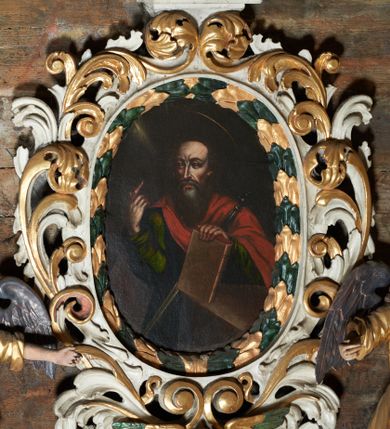Zdjęcie nr 1: Obraz w kształcie stojącego owalu z przedstawieniem św. Pawła. Święty ukazany w półpostaci, delikatnie zwrócony w prawo, prawą ręką podnoszący palec wskazujący, a lewą wspierający się na księdze, opierając ją o stół. O jego lewe ramię oparty miecz. Twarz podłużna o wyraźnie podkreślonych kościach policzkowych, z długim nosem i dużymi oczami, wysokim czołem, okolona długą i częściowo siwą brodą. Włosy średniej długości, ciemnobrązowe. Nad głową ma złoty i okrągły nimb. Ubrany jest w zieloną suknię z długimi rękawami oraz czerwony płaszcz, zapięty na prawym ramieniu. Tło obrazu jednolite, ciemnobrązowe, z delikatną smugą żółtego światła, padającą z lewej, górnej strony obrazu. Rama drewniana, rzeźbiona z wici wawrzynu, o listkach naprzemiennie malowanych na zielono i złoto.