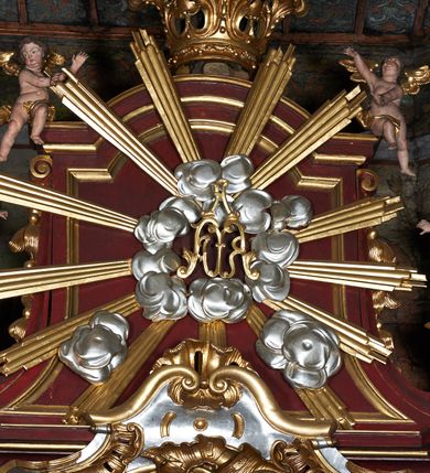 Zdjęcie nr 9: Nastawa ołtarzowa jednokondygnacyjna, jednoosiowa, ze zwieńczeniem, ustawiona na dwustrefowym cokole. Ołtarz prostopadłościenny, z antepedium w kształcie leżącego prostokąta. W polu malowane symbole: skrzyżowane kotwica i krzyż oraz gorejące serce pośrodku. Tabernakulum nowe, w kształcie prostopadłościennej skrzynki z tronem wystawienia, zamkniętym łukiem półkolistym. Na drzwiczkach tabernakulum płaskorzeźbiony kielich i winne grona. Nastawa flankowana parami ukośnie ustawionych i zdwojonych, kanelowanych pilastrów oraz parą stojących przed nimi kolumn o kręconych trzonach. Podpory podtrzymują wyłamane nad osią główną belkowanie, z segmentowymi przyczółkami po bokach. W polu środkowym, w profilowanej ramie, zamkniętej łukiem wklęsło-wypukłym obraz Matki Boskiej Śnieżnej; na zasuwie obraz św. Jakuba Apostoła. Zwieńczenie w kształcie stojącego prostokąta, zamkniętego łukiem nadwieszonym, ujęte po bokach wolutami i zwisami kampanul. W polu płaskorzeźbiona gloria złożona z wiązek promieni o nierównej długości, z monogramem Marii otoczonym obłokami pośrodku. U szczytu korona w typie otwartym. Na przyczółkach oraz na krawędziach zwieńczenia usadzone cztery aniołki w teatralnych pozach. Po bokach nastawy ażurowe uszy złożone z ornamentu rocaille’owego i motywu kratki. Struktura polichromowana w kolorze bordowym, profilowania, ornamentyka i detale złocone i srebrzone.
