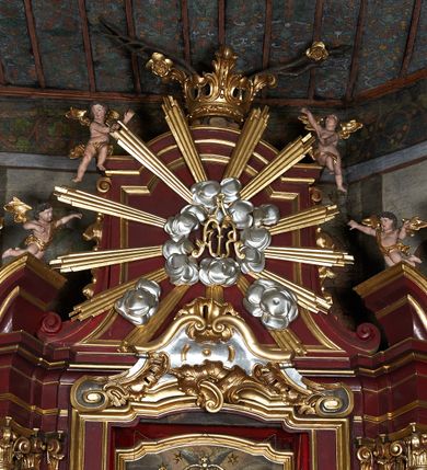 Zdjęcie nr 8: Nastawa ołtarzowa jednokondygnacyjna, jednoosiowa, ze zwieńczeniem, ustawiona na dwustrefowym cokole. Ołtarz prostopadłościenny, z antepedium w kształcie leżącego prostokąta. W polu malowane symbole: skrzyżowane kotwica i krzyż oraz gorejące serce pośrodku. Tabernakulum nowe, w kształcie prostopadłościennej skrzynki z tronem wystawienia, zamkniętym łukiem półkolistym. Na drzwiczkach tabernakulum płaskorzeźbiony kielich i winne grona. Nastawa flankowana parami ukośnie ustawionych i zdwojonych, kanelowanych pilastrów oraz parą stojących przed nimi kolumn o kręconych trzonach. Podpory podtrzymują wyłamane nad osią główną belkowanie, z segmentowymi przyczółkami po bokach. W polu środkowym, w profilowanej ramie, zamkniętej łukiem wklęsło-wypukłym obraz Matki Boskiej Śnieżnej; na zasuwie obraz św. Jakuba Apostoła. Zwieńczenie w kształcie stojącego prostokąta, zamkniętego łukiem nadwieszonym, ujęte po bokach wolutami i zwisami kampanul. W polu płaskorzeźbiona gloria złożona z wiązek promieni o nierównej długości, z monogramem Marii otoczonym obłokami pośrodku. U szczytu korona w typie otwartym. Na przyczółkach oraz na krawędziach zwieńczenia usadzone cztery aniołki w teatralnych pozach. Po bokach nastawy ażurowe uszy złożone z ornamentu rocaille’owego i motywu kratki. Struktura polichromowana w kolorze bordowym, profilowania, ornamentyka i detale złocone i srebrzone.
