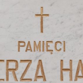 Zdjęcie nr 1: Kamienna tablica w kształcie leżącego prostokąta z wyrytą poniżej krzyża łacińskiego, złocona inskrypcją „+PAMIĘCI / KAZIMIERZA HALLERA / Z JURCZYC / ZAMORDOWANEGO PRZEZ NIEMCÓW / W OŚWIĘCIMIU W R(OKU) 1942 / W 36 R(OKU) ŻYCIA”. W narożach  rozety maskujące miejsca mocowania. 