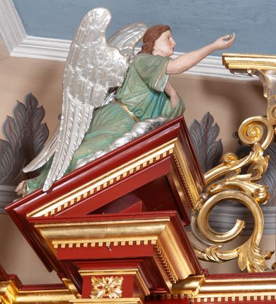 Zdjęcie nr 38: Ołtarz architektoniczny, trójosiowy, jednokondygnacyjny ze zwieńczeniem, na cokole. Mensa prostopadłościenna, drewniana, z portatylem. Antepedium na profilowanej podstawie podzielone na trzy bliskie kwadratom płyciny. Metalowe tabernakulum w formie prostopadłościanu ujętego wolutami z liści. Na ścianie frontowej drzwiczki dekorowane hostią z literami IHS ujętą od dołu rozłożonymi dłońmi.  Osie nastawy wydzielone dwiema parami pilastrów i stojącymi przed licem ołtarza kolumnami z kapitelami kompozytowymi. Wewnętrzna para kolumn dźwiga imposty z przerwanym przyczółkiem, na którym siedzi para klęczących aniołów, zaś zewnętrzna para dźwiga imposty z aniołami półleżącymi. Pole środkowe tworzy szeroka, wypełniona ażurowym akantem i rozetami rama w formie stojącego prostokąta zamkniętego łukiem nadwieszonym, ujęta lizenami, podtrzymywana przez konsole, z obrazem św. Wawrzyńca wymiennie z obrazem św. Józefa oraz rzeźbionym krucyfiksem. W osiach bocznych figury św. Stanisława po lewej i św. Wojciecha po prawej stronie, na tle arkad z ażurową kratką. Zwieńczenie tworzy grupa rzeźbiarska z przedstawieniem Trójcy Świętej. Bóg Ojciec i Chrystus siedzą zwróceni do siebie, na tle ulistionych wolut, które podtrzymują gołębicę Ducha Świetego, nad którą unosi się Oko Opatrzności. Grupa jest flankowana przez jońskie kolumny ze zwróconymi na zewnątrz wolutami, ujęta fragmentami wici tworzącymi spływy wolutowe. Cokoły kolumn dekorowane płycinami z akantem, rozetą i liliami heraldycznymi, zwieńczone ząbkowaniem. W przyłuczach dekoracja roślinna. Płycinę lizen zdobią festony z wstęgą regencyjną. Trzony pilastrów podzielone na dwie płyciny o wklęsłych bokach, dekorowane rozetami. Architrawy i fryzy dekorowane rozetami z akantu, gzyms z ząbkowaniem. Kolumny zwieńczenia dekorowane akantowymi spływami wolutowymi. Ołtarz polichromowany na ciemnoczerwono; ornamentyka oraz detale architektoniczne złocone i srebrzone. 