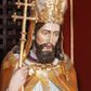 Zdjęcie nr 1: Figura drążona, na cokole. Święty Wojciech został ukazany w pozycji stojącej z uniesionymi rękami, w prawej trzyma podwójny krzyż misyjny, w lewej zaś, przy piersi, oprawioną w czerwień księgę z zaznaczonym palcem fragmentem. Twarz ma pociągłą, brwi wąskie, oczy szeroko otwarte, nos prosty, wąski i długą, sięgającą dekoltu brodę. Postać jest ubrana w fioletową albę, białą komżę ze złoconą bordiurą i ściśle przylegającą do ciała pomarańczową kapę, podbitą zielenią. Na nią ma załozony złoty paliusz, na głowie infułę, na nogach ciemnobrązowe buty. Draperia delikatnie fałdowana, odzwierciedla układ ciała. W partiach ciała polichromia naturalistyczna.