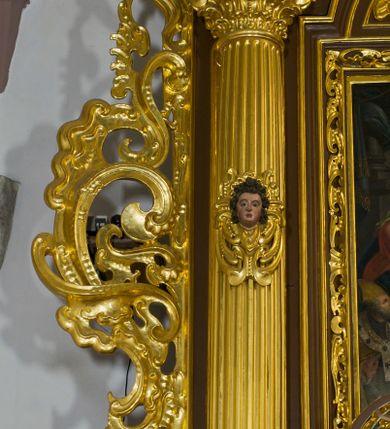 Zdjęcie nr 42: Ołtarz drewniany, architektoniczny, jednoosiowy, jednokondygnacyjny, ze zwieńczeniem, z dwiema bramkami. Jest umieszczony na murowanym, dwustopniowym podwyższeniu. Podstawa ołtarza murowana, skrzyniowa o kształcie prostopadłościanu, o obudowie drewnianej. Brak kamiennej mensy ołtarzowej. W partii antepedium nisza w kształcie prostokąta leżącego. Na mensie ustawione tabernakulum w formie centralnego kościółka zwieńczonego kopułą z latarnią.

Retabulum jest flankowane dwiema złoconymi kolumnami kompozytowymi, ustawionymi na profilowanych cokołach. Trzony kolumn są kanelowane, ozdobione w połowie wysokości główkami aniołków ujętymi dekoracją chrząstkową. Kolumny dźwigają belkowanie z wydatnym, przełamującym się nad nimi gzymsem, ozdobione ornamentem małżowinowym. W polu środkowym ołtarza profilowana, złocona i malowana rama z górną krawędzią w formie arkady z kluczem, dolna krawędź zaakcentowana uskokiem. W niej druga rama, prostokątna, ozdobiona ornamentem małżowinowym i złocona, z obrazem przedstawiającym Św. Annę Samotrzeć w otoczeniu świętych. We wnęce, za zasuwą, widnieje obraz Matki Boskiej z Dzieciątkiem w prostokątnej ramie, rzeźbionej i złoconej, pokrytej ornamentem roślinnym. Wnęka pokryta ciemnoczerwonym aksamitem, poniżej obrazu zawieszone wota. W polu arkady, w półkolistym tympanonie, na tle złoconych obłoków srebrna gołębica Ducha Świętego. Na gzymsie, na osi kolumn wazony z kwiatami. Po bokach retabulum bogato rzeźbione i złocone uszy z bujnym ornamentem małżowinowym. W zwieńczeniu, w owalnej, profilowanej i złoconej ramie obraz przedstawiający Wniebowzięcie Najświętszej Marii Panny. Rama otoczona szeroko rozbudowaną ornamentyką małżowinową. Po bokach ołtarza bramki prowadzące za ołtarz, o kształcie prostokąta stojącego, ze zwieńczeniem w formie łuku kotarowego zamkniętego od góry prostym odcinkiem, z profilowanym cokołem (pod figurę) z podwieszonym ornamentem w kształcie muszli. Górne narożniki bramek podkreślone złoconym ornamentem w kształcie wolut z elementem roślinnym. Otwór wejściowy, w kształcie analogicznym do bramki, z profilowanymi krawędziami, zakryty kotarą z aksamitu w kolorze ciemnoczerwonym. Struktura ołtarza polichromowana w kolorze ciemnobrązowym. Kolumny, pilastry, profilowania i dekoracja rzeźbiarska złocone.