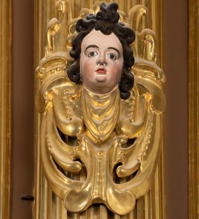 Zdjęcie nr 16: Ołtarz drewniany, architektoniczny, jednoosiowy, jednokondygnacyjny, ze zwieńczeniem, z dwiema bramkami. Jest umieszczony na murowanym, dwustopniowym podwyższeniu. Podstawa ołtarza murowana, skrzyniowa o kształcie prostopadłościanu, o obudowie drewnianej. Brak kamiennej mensy ołtarzowej. W partii antepedium nisza w kształcie prostokąta leżącego. Na mensie ustawione tabernakulum w formie centralnego kościółka zwieńczonego kopułą z latarnią.

Retabulum jest flankowane dwiema złoconymi kolumnami kompozytowymi, ustawionymi na profilowanych cokołach. Trzony kolumn są kanelowane, ozdobione w połowie wysokości główkami aniołków ujętymi dekoracją chrząstkową. Kolumny dźwigają belkowanie z wydatnym, przełamującym się nad nimi gzymsem, ozdobione ornamentem małżowinowym. W polu środkowym ołtarza profilowana, złocona i malowana rama z górną krawędzią w formie arkady z kluczem, dolna krawędź zaakcentowana uskokiem. W niej druga rama, prostokątna, ozdobiona ornamentem małżowinowym i złocona, z obrazem przedstawiającym Św. Annę Samotrzeć w otoczeniu świętych. We wnęce, za zasuwą, widnieje obraz Matki Boskiej z Dzieciątkiem w prostokątnej ramie, rzeźbionej i złoconej, pokrytej ornamentem roślinnym. Wnęka pokryta ciemnoczerwonym aksamitem, poniżej obrazu zawieszone wota. W polu arkady, w półkolistym tympanonie, na tle złoconych obłoków srebrna gołębica Ducha Świętego. Na gzymsie, na osi kolumn wazony z kwiatami. Po bokach retabulum bogato rzeźbione i złocone uszy z bujnym ornamentem małżowinowym. W zwieńczeniu, w owalnej, profilowanej i złoconej ramie obraz przedstawiający Wniebowzięcie Najświętszej Marii Panny. Rama otoczona szeroko rozbudowaną ornamentyką małżowinową. Po bokach ołtarza bramki prowadzące za ołtarz, o kształcie prostokąta stojącego, ze zwieńczeniem w formie łuku kotarowego zamkniętego od góry prostym odcinkiem, z profilowanym cokołem (pod figurę) z podwieszonym ornamentem w kształcie muszli. Górne narożniki bramek podkreślone złoconym ornamentem w kształcie wolut z elementem roślinnym. Otwór wejściowy, w kształcie analogicznym do bramki, z profilowanymi krawędziami, zakryty kotarą z aksamitu w kolorze ciemnoczerwonym. Struktura ołtarza polichromowana w kolorze ciemnobrązowym. Kolumny, pilastry, profilowania i dekoracja rzeźbiarska złocone.