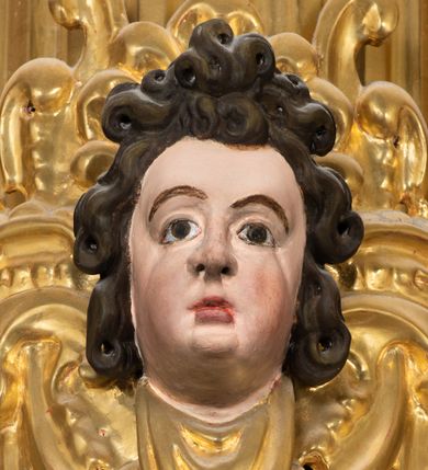 Zdjęcie nr 15: Ołtarz drewniany, architektoniczny, jednoosiowy, jednokondygnacyjny, ze zwieńczeniem, z dwiema bramkami. Jest umieszczony na murowanym, dwustopniowym podwyższeniu. Podstawa ołtarza murowana, skrzyniowa o kształcie prostopadłościanu, o obudowie drewnianej. Brak kamiennej mensy ołtarzowej. W partii antepedium nisza w kształcie prostokąta leżącego. Na mensie ustawione tabernakulum w formie centralnego kościółka zwieńczonego kopułą z latarnią.

Retabulum jest flankowane dwiema złoconymi kolumnami kompozytowymi, ustawionymi na profilowanych cokołach. Trzony kolumn są kanelowane, ozdobione w połowie wysokości główkami aniołków ujętymi dekoracją chrząstkową. Kolumny dźwigają belkowanie z wydatnym, przełamującym się nad nimi gzymsem, ozdobione ornamentem małżowinowym. W polu środkowym ołtarza profilowana, złocona i malowana rama z górną krawędzią w formie arkady z kluczem, dolna krawędź zaakcentowana uskokiem. W niej druga rama, prostokątna, ozdobiona ornamentem małżowinowym i złocona, z obrazem przedstawiającym Św. Annę Samotrzeć w otoczeniu świętych. We wnęce, za zasuwą, widnieje obraz Matki Boskiej z Dzieciątkiem w prostokątnej ramie, rzeźbionej i złoconej, pokrytej ornamentem roślinnym. Wnęka pokryta ciemnoczerwonym aksamitem, poniżej obrazu zawieszone wota. W polu arkady, w półkolistym tympanonie, na tle złoconych obłoków srebrna gołębica Ducha Świętego. Na gzymsie, na osi kolumn wazony z kwiatami. Po bokach retabulum bogato rzeźbione i złocone uszy z bujnym ornamentem małżowinowym. W zwieńczeniu, w owalnej, profilowanej i złoconej ramie obraz przedstawiający Wniebowzięcie Najświętszej Marii Panny. Rama otoczona szeroko rozbudowaną ornamentyką małżowinową. Po bokach ołtarza bramki prowadzące za ołtarz, o kształcie prostokąta stojącego, ze zwieńczeniem w formie łuku kotarowego zamkniętego od góry prostym odcinkiem, z profilowanym cokołem (pod figurę) z podwieszonym ornamentem w kształcie muszli. Górne narożniki bramek podkreślone złoconym ornamentem w kształcie wolut z elementem roślinnym. Otwór wejściowy, w kształcie analogicznym do bramki, z profilowanymi krawędziami, zakryty kotarą z aksamitu w kolorze ciemnoczerwonym. Struktura ołtarza polichromowana w kolorze ciemnobrązowym. Kolumny, pilastry, profilowania i dekoracja rzeźbiarska złocone.