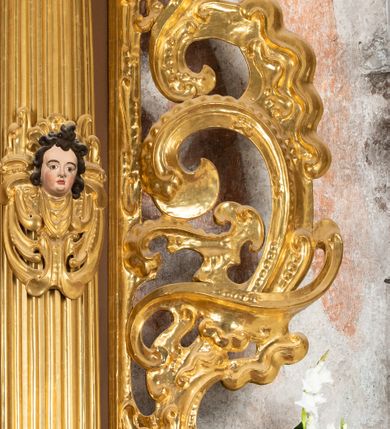 Zdjęcie nr 25: Ołtarz drewniany, architektoniczny, jednoosiowy, jednokondygnacyjny, ze zwieńczeniem, z dwiema bramkami. Jest umieszczony na murowanym, dwustopniowym podwyższeniu. Podstawa ołtarza murowana, skrzyniowa o kształcie prostopadłościanu, o obudowie drewnianej. Brak kamiennej mensy ołtarzowej. W partii antepedium nisza w kształcie prostokąta leżącego. Na mensie ustawione tabernakulum w formie centralnego kościółka zwieńczonego kopułą z latarnią.

Retabulum jest flankowane dwiema złoconymi kolumnami kompozytowymi, ustawionymi na profilowanych cokołach. Trzony kolumn są kanelowane, ozdobione w połowie wysokości główkami aniołków ujętymi dekoracją chrząstkową. Kolumny dźwigają belkowanie z wydatnym, przełamującym się nad nimi gzymsem, ozdobione ornamentem małżowinowym. W polu środkowym ołtarza profilowana, złocona i malowana rama z górną krawędzią w formie arkady z kluczem, dolna krawędź zaakcentowana uskokiem. W niej druga rama, prostokątna, ozdobiona ornamentem małżowinowym i złocona, z obrazem przedstawiającym Św. Annę Samotrzeć w otoczeniu świętych. We wnęce, za zasuwą, widnieje obraz Matki Boskiej z Dzieciątkiem w prostokątnej ramie, rzeźbionej i złoconej, pokrytej ornamentem roślinnym. Wnęka pokryta ciemnoczerwonym aksamitem, poniżej obrazu zawieszone wota. W polu arkady, w półkolistym tympanonie, na tle złoconych obłoków srebrna gołębica Ducha Świętego. Na gzymsie, na osi kolumn wazony z kwiatami. Po bokach retabulum bogato rzeźbione i złocone uszy z bujnym ornamentem małżowinowym. W zwieńczeniu, w owalnej, profilowanej i złoconej ramie obraz przedstawiający Wniebowzięcie Najświętszej Marii Panny. Rama otoczona szeroko rozbudowaną ornamentyką małżowinową. Po bokach ołtarza bramki prowadzące za ołtarz, o kształcie prostokąta stojącego, ze zwieńczeniem w formie łuku kotarowego zamkniętego od góry prostym odcinkiem, z profilowanym cokołem (pod figurę) z podwieszonym ornamentem w kształcie muszli. Górne narożniki bramek podkreślone złoconym ornamentem w kształcie wolut z elementem roślinnym. Otwór wejściowy, w kształcie analogicznym do bramki, z profilowanymi krawędziami, zakryty kotarą z aksamitu w kolorze ciemnoczerwonym. Struktura ołtarza polichromowana w kolorze ciemnobrązowym. Kolumny, pilastry, profilowania i dekoracja rzeźbiarska złocone.