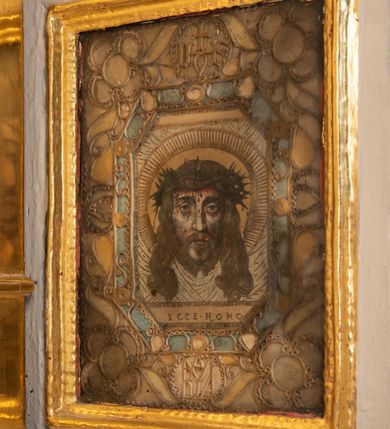 Zdjęcie nr 37: Ołtarz drewniany, architektoniczny, jednoosiowy, jednokondygnacyjny, ze zwieńczeniem, z dwiema bramkami. Jest umieszczony na murowanym, dwustopniowym podwyższeniu. Podstawa ołtarza murowana, skrzyniowa o kształcie prostopadłościanu, o obudowie drewnianej. Brak kamiennej mensy ołtarzowej. W partii antepedium nisza w kształcie prostokąta leżącego. Na mensie ustawione tabernakulum w formie centralnego kościółka zwieńczonego kopułą z latarnią.

Retabulum jest flankowane dwiema złoconymi kolumnami kompozytowymi, ustawionymi na profilowanych cokołach. Trzony kolumn są kanelowane, ozdobione w połowie wysokości główkami aniołków ujętymi dekoracją chrząstkową. Kolumny dźwigają belkowanie z wydatnym, przełamującym się nad nimi gzymsem, ozdobione ornamentem małżowinowym. W polu środkowym ołtarza profilowana, złocona i malowana rama z górną krawędzią w formie arkady z kluczem, dolna krawędź zaakcentowana uskokiem. W niej druga rama, prostokątna, ozdobiona ornamentem małżowinowym i złocona, z obrazem przedstawiającym Św. Annę Samotrzeć w otoczeniu świętych. We wnęce, za zasuwą, widnieje obraz Matki Boskiej z Dzieciątkiem w prostokątnej ramie, rzeźbionej i złoconej, pokrytej ornamentem roślinnym. Wnęka pokryta ciemnoczerwonym aksamitem, poniżej obrazu zawieszone wota. W polu arkady, w półkolistym tympanonie, na tle złoconych obłoków srebrna gołębica Ducha Świętego. Na gzymsie, na osi kolumn wazony z kwiatami. Po bokach retabulum bogato rzeźbione i złocone uszy z bujnym ornamentem małżowinowym. W zwieńczeniu, w owalnej, profilowanej i złoconej ramie obraz przedstawiający Wniebowzięcie Najświętszej Marii Panny. Rama otoczona szeroko rozbudowaną ornamentyką małżowinową. Po bokach ołtarza bramki prowadzące za ołtarz, o kształcie prostokąta stojącego, ze zwieńczeniem w formie łuku kotarowego zamkniętego od góry prostym odcinkiem, z profilowanym cokołem (pod figurę) z podwieszonym ornamentem w kształcie muszli. Górne narożniki bramek podkreślone złoconym ornamentem w kształcie wolut z elementem roślinnym. Otwór wejściowy, w kształcie analogicznym do bramki, z profilowanymi krawędziami, zakryty kotarą z aksamitu w kolorze ciemnoczerwonym. Struktura ołtarza polichromowana w kolorze ciemnobrązowym. Kolumny, pilastry, profilowania i dekoracja rzeźbiarska złocone.