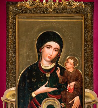 Zdjęcie nr 2: W polu o kształcie stojącego prostokąta, ukazana Matka Boska w półpostaci, w ujęciu frontalnym z Dzieciątkiem podtrzymywanym na lewym ramieniu. Głowa Marii lekko pochylona w stronę Jezusa. Twarz ukazana niemal frontalnie, wydłużona, zwężająca się ku dołowi, oczy duże o ciężkich powiekach, podkreślone ciemną kreską, prosty wąski nos i małe usta. Wzrok Marii skierowany bezpośrednio na widza. Prawa dłoń wąska, o bardzo wydłużonych palcach, ułożona poziomo, sztywno wyprostowana z odwiedzionym kciukiem, wskazuje na Dzieciątko, lewa dłoń przytrzymuje jego nogi. 
Maria jest ubrana w płaszcz okrywający głowę, układający się miękkimi fałdami i spięty pod szyją ozdobną broszą ze złocistym laserunkiem. Płaszcz, pierwotnie ciemnobłękitny, obecnie zzieleniały (rozłożony azuryt), ozdobiony niesymetrycznie rozmieszczonym, złoconym ornamentem patronowym (rozetki w dwóch rodzajach wzorów) i obszyty na brzegach wąskim złoconym paskiem, ponad którym widnieje koronka z ornamentu w kształcie trójliścia. Podszewka, widoczna w odwinięciach przy twarzy i w fałdach poniżej prawej dłoni, ciemnoczerwona. Spod płaszcza, na głowie wystaje rąbek białej, bardzo delikatnie malowanej, przezroczystej chusty. Ukazująca się spod płaszcza suknia Marii ciemnobłękitna, o półokrągłym wykroju przy szyi i wąskim rękawie. Lamówkę i mankiet rękawa tworzy szeroki pas złocistego obszycia ozdobionego koronką analogiczną do obszycia płaszcza.
Jezus jest ukazany w pozycji siedzącej, lekko pochylony ku Matce, z głową zwróconą w jej kierunku. Chrystus unosi prawą rękę w geście błogosławieństwa, w lewej trzyma wsparty o kolano ewangeliarz. Stopy Jezusa, zwłaszcza lewa, o nienaturalnie długich, wąskich palcach, zaś prawa odwrócona. Dzieciątko ubrane w tunikę w kolorze czerwieni złamanej brązem (przemytej), z rozmieszczonym nieregularnie złotym ornamentem patronowym i szerokim złoconym obszyciem, pośrodku którego biegnie zygzakowata linia, tworząca trójkąty z wpisaną formą trójliścia. Patron na tunice złożony z dwóch odwróconych do siebie półksiężyców z poziomo biegnącymi promieniami. Tunika ma jasnozieloną podszewkę, widoczną w odwinięciu nad prawą nóżką. Fałdy szaty układające się miękko, ledwo widoczne, z wyjątkiem charakterystycznej fałdy przy szyi Dzieciątka. 
Księga trzymana przez Jezusa, przedstawiona grzbietem na zewnątrz, z czerwoną oprawą z dwoma złotymi wąskimi okuciami i pięcioma zielonymi rautami, rozmieszczonymi w rogach i na środku okładki. Pomiędzy okładkami widoczne białe brzegi kart. 
Karnacje Marii i Jezusa malowane intensywnym różem, modelowanym bielą i szarością. Włosy okalające głowę Dzieciątka, ułożone ornamentalnie, brunatne z pasmami bladej żółcieni. Nimby Matki Boskiej i Dzieciątka, zaznaczone pucowanym ornamentem w kształcie trójliścia występującego na sukni i płaszczu Marii, zachodzące na siebie. Tło obrazu złocone, na desce lipowej przymocowanej do ramy, w której umieszczono obraz.