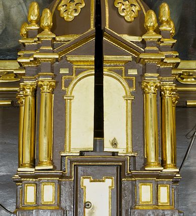 Zdjęcie nr 1: Tabernakulum w formie centralnego kościoła z kopułą. Całość na wysokim profilowanym cokole, flankującym właściwe Sakramentarium, z drzwiczkami w kształcie stojącego prostokąta, ozdobionymi płyciną z uszakami w górnych narożnikach, ujętymi od góry nadwieszonym prostokątnym profilowanym obramieniem. Na cokole cztery pary kolumn korynckich ustawionych uskokowo, flankujących centralną arkadę zakończoną łukiem półkolistym. Kolumny dźwigają belkowanie z wydatnym przełamującym się gzymsem, zwieńczone trójkątnym profilowanym przyczółkiem. Ponad kolumnami, ustawione na profilowanych impostach dekoracyjne szyszki. Kopuła z pionowymi podziałami, ozdobionymi ornamentem małżowinowym, zwieńczona latarnią z przeźroczami w postaci półkolistych arkad i kopułką. Całość zwieńczona krzyżem o ramionach zakończonych trójliściem. 
Górna część tabernakulum wraz z kopułą otwierana drzwiczkami dwuskrzydłowymi, łamanymi, dwuelementowymi. Wewnątrz na ścianach podziały architektoniczne zaznaczone korynckimi pilastrami wspierającymi belkowanie, ustawionymi na wysokich cokołach. W części środkowej pilastry dźwigają belkowanie z przełamującym się gzymsem i zwieńczeniem trójkątnym przerwanym, ozdobionym motywem złożonym z ornamentu małżowinowego. W polu tympanonu i belkowania rozeta inkrustowana bursztynem, ujęta ramą w kształcie sześcioboku. Na ścianach wewnętrznych obrazki relikwiarzowe, w profilowanych ramach, oszklone. W środkowym przedstawienie św. Katarzyny Sieneńskiej z aniołami, nad nim owalne pole wpisane w oktagon z owalną kasztą obwiedzione kwiatami i glorią promienistą, w kwiatach wydrukowane słowa: &quot;AGNUS OMBRA DE [...]&quot;. Na dwóch lewych ściankach tkany wizerunek Matki Boskiej Krakowskiej z podpisem: &quot; IMAGO M. MIRACVLOSA B(EATAE) V(IRGINIS) M(ARIAE) / IN ECCLESIA CARMELITA/NVM CRACOVIE IN ARENIS&quot; oraz relikwie w owalnej kaszcie obwiedzionej abstrakcyjnym, symetrycznym wzorem wykonanym z metalowych blaszek. Na ściankach z prawej strony owalne przedstawienie św. Katarzyny Aleksandryjskiej otoczone stylizowanymi wiciami z blaszek i relikwiami wielu świętych opisanych na banderolach oraz przedstawienie Ecce Homo z podpisem &quot;ECCE HOMO&quot; i monogramem imienia Jezus (u góry) i maryjsnym (u dołu). Podniebie kopuły wypełnione perspektywicznymi kasetonami ozdobionymi ornamentem małżowinowym. Struktura tabernakulum w kolorze ciemnobrązowym, pola arkady, płyciny i pola wewnętrzne jasnobeżowe, pola kasetonów niebieskie, kolumny, pilastry, profilowania i ornamenty złocone.