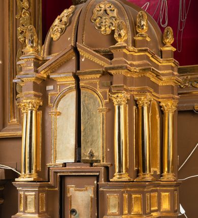 Zdjęcie nr 4: Tabernakulum w formie centralnego kościoła z kopułą. Całość na wysokim profilowanym cokole, flankującym właściwe Sakramentarium, z drzwiczkami w kształcie stojącego prostokąta, ozdobionymi płyciną z uszakami w górnych narożnikach, ujętymi od góry nadwieszonym prostokątnym profilowanym obramieniem. Na cokole cztery pary kolumn korynckich ustawionych uskokowo, flankujących centralną arkadę zakończoną łukiem półkolistym. Kolumny dźwigają belkowanie z wydatnym przełamującym się gzymsem, zwieńczone trójkątnym profilowanym przyczółkiem. Ponad kolumnami, ustawione na profilowanych impostach dekoracyjne szyszki. Kopuła z pionowymi podziałami, ozdobionymi ornamentem małżowinowym, zwieńczona latarnią z przeźroczami w postaci półkolistych arkad i kopułką. Całość zwieńczona krzyżem o ramionach zakończonych trójliściem. 
Górna część tabernakulum wraz z kopułą otwierana drzwiczkami dwuskrzydłowymi, łamanymi, dwuelementowymi. Wewnątrz na ścianach podziały architektoniczne zaznaczone korynckimi pilastrami wspierającymi belkowanie, ustawionymi na wysokich cokołach. W części środkowej pilastry dźwigają belkowanie z przełamującym się gzymsem i zwieńczeniem trójkątnym przerwanym, ozdobionym motywem złożonym z ornamentu małżowinowego. W polu tympanonu i belkowania rozeta inkrustowana bursztynem, ujęta ramą w kształcie sześcioboku. Na ścianach wewnętrznych obrazki relikwiarzowe, w profilowanych ramach, oszklone. W środkowym przedstawienie św. Katarzyny Sieneńskiej z aniołami, nad nim owalne pole wpisane w oktagon z owalną kasztą obwiedzione kwiatami i glorią promienistą, w kwiatach wydrukowane słowa: "AGNUS OMBRA DE [...]". Na dwóch lewych ściankach tkany wizerunek Matki Boskiej Krakowskiej z podpisem: " IMAGO M. MIRACVLOSA B(EATAE) V(IRGINIS) M(ARIAE) / IN ECCLESIA CARMELITA/NVM CRACOVIE IN ARENIS" oraz relikwie w owalnej kaszcie obwiedzionej abstrakcyjnym, symetrycznym wzorem wykonanym z metalowych blaszek. Na ściankach z prawej strony owalne przedstawienie św. Katarzyny Aleksandryjskiej otoczone stylizowanymi wiciami z blaszek i relikwiami wielu świętych opisanych na banderolach oraz przedstawienie Ecce Homo z podpisem "ECCE HOMO" i monogramem imienia Jezus (u góry) i maryjsnym (u dołu). Podniebie kopuły wypełnione perspektywicznymi kasetonami ozdobionymi ornamentem małżowinowym. Struktura tabernakulum w kolorze ciemnobrązowym, pola arkady, płyciny i pola wewnętrzne jasnobeżowe, pola kasetonów niebieskie, kolumny, pilastry, profilowania i ornamenty złocone.