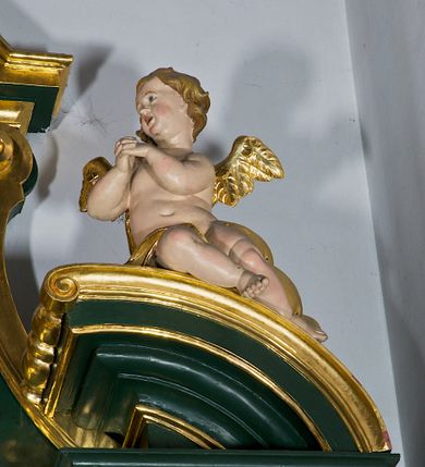 Zdjęcie nr 52: Ołtarz przyścienny, architektoniczny, jednokondygnacyjny, jednoosiowy ze zwieńczeniem. Umieszczony na dwustopniowym, kamiennym podwyższeniu. Mensa prostopadłościenna, z portatylem i współczesnym antepedium ozdobionym postacią św. Weroniki trzymającej chustę z odbiciem twarzy Chrystusa (veraikon) i rzeźbionym ornamentem ze srebrzonych liści i złoconych kiści winogron; tło w kolorze struktury ołtarza. Retabulum na wysokim profilowanym, dwustopniowym cokole, flankowane zwielokrotnionymi pilastrami z jońskimi kapitelami. Pilastry dźwigają przerwane belkowanie z wydatnym profilowanym gzymsem z przerwanym przyczółkiem. Zwieńczenie o wklęsłych bokach ujęte spływami wolutowymi dźwigającymi gzyms w formie nadwieszonego łuku odcinkowego. Na tle pilastrów ustawione na profilowanych impostach rzeźby: po prawej stronie św. Wojciecha, po lewej św. Stanisława. Na przyczółkach znajdują się siedzące putta. Pole środkowe o kształcie prostokąta stojącego od góry zamkniętego łukiem półkolistym nadwieszonym, w kluczu ornament z motywu rocaille. Wewnątrz pola ujęty profilowaną, złoconą ramą obraz z przedstawieniem św. Mikołaja z Miry. W zwieńczeniu obraz w ramie z wklęsłymi bokami i wypukłymi dolną i górną krawędzią przedstawiający św. Marię Magdalenę. Nastawę ujmują ornamentalne uszy, utworzone z motywów rocaille'owych i liściasto-kwiatowych zwisów. Na kapitele są nałożone rocaille'owe kartusze, a pod nimi podwieszone zwisające ulistnione i ukwiecone gałązki wzbogacone motywami rocaille'ów. Struktura ołtarza polichromowana w kolorze ciemnozielonym. Bazy pilastrów, kapitele, uszy, ornamenty, profilowania, obramienia płycin i ramy obrazów złocone. Rzeźby świętych złocone, srebrzone i polichromowane. Rzeźby aniołków złocone i polichromowane.

