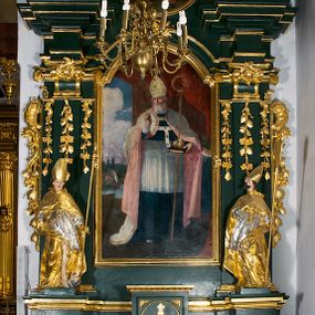 Zdjęcie nr 1: Ołtarz przyścienny, architektoniczny, jednokondygnacyjny, jednoosiowy ze zwieńczeniem. Umieszczony na dwustopniowym, kamiennym podwyższeniu. Mensa prostopadłościenna, z portatylem i współczesnym antepedium ozdobionym postacią św. Weroniki trzymającej chustę z odbiciem twarzy Chrystusa (veraikon) i rzeźbionym ornamentem ze srebrzonych liści i złoconych kiści winogron; tło w kolorze struktury ołtarza. Retabulum na wysokim profilowanym, dwustopniowym cokole, flankowane zwielokrotnionymi pilastrami z jońskimi kapitelami. Pilastry dźwigają przerwane belkowanie z wydatnym profilowanym gzymsem z przerwanym przyczółkiem. Zwieńczenie o wklęsłych bokach ujęte spływami wolutowymi dźwigającymi gzyms w formie nadwieszonego łuku odcinkowego. Na tle pilastrów ustawione na profilowanych impostach rzeźby: po prawej stronie św. Wojciecha, po lewej św. Stanisława. Na przyczółkach znajdują się siedzące putta. Pole środkowe o kształcie prostokąta stojącego od góry zamkniętego łukiem półkolistym nadwieszonym, w kluczu ornament z motywu rocaille. Wewnątrz pola ujęty profilowaną, złoconą ramą obraz z przedstawieniem św. Mikołaja z Miry. W zwieńczeniu obraz w ramie z wklęsłymi bokami i wypukłymi dolną i górną krawędzią przedstawiający św. Marię Magdalenę. Nastawę ujmują ornamentalne uszy, utworzone z motywów rocaille'owych i liściasto-kwiatowych zwisów. Na kapitele są nałożone rocaille'owe kartusze, a pod nimi podwieszone zwisające ulistnione i ukwiecone gałązki wzbogacone motywami rocaille'ów. Struktura ołtarza polichromowana w kolorze ciemnozielonym. Bazy pilastrów, kapitele, uszy, ornamenty, profilowania, obramienia płycin i ramy obrazów złocone. Rzeźby świętych złocone, srebrzone i polichromowane. Rzeźby aniołków złocone i polichromowane.

