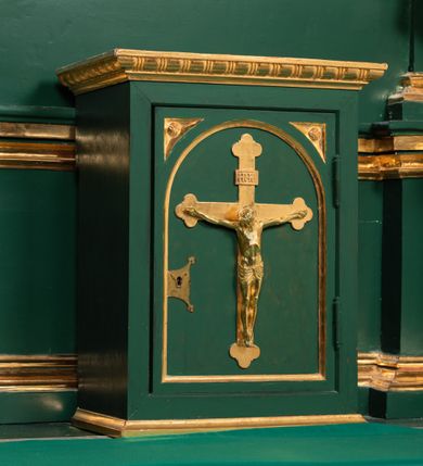 Zdjęcie nr 7: Ołtarz przyścienny, architektoniczny, jednokondygnacyjny, jednoosiowy ze zwieńczeniem. Umieszczony na dwustopniowym, kamiennym podwyższeniu. Mensa prostopadłościenna, z portatylem i współczesnym antepedium ozdobionym postacią św. Weroniki trzymającej chustę z odbiciem twarzy Chrystusa (veraikon) i rzeźbionym ornamentem ze srebrzonych liści i złoconych kiści winogron; tło w kolorze struktury ołtarza. Retabulum na wysokim profilowanym, dwustopniowym cokole, flankowane zwielokrotnionymi pilastrami z jońskimi kapitelami. Pilastry dźwigają przerwane belkowanie z wydatnym profilowanym gzymsem z przerwanym przyczółkiem. Zwieńczenie o wklęsłych bokach ujęte spływami wolutowymi dźwigającymi gzyms w formie nadwieszonego łuku odcinkowego. Na tle pilastrów ustawione na profilowanych impostach rzeźby: po prawej stronie św. Wojciecha, po lewej św. Stanisława. Na przyczółkach znajdują się siedzące putta. Pole środkowe o kształcie prostokąta stojącego od góry zamkniętego łukiem półkolistym nadwieszonym, w kluczu ornament z motywu rocaille. Wewnątrz pola ujęty profilowaną, złoconą ramą obraz z przedstawieniem św. Mikołaja z Miry. W zwieńczeniu obraz w ramie z wklęsłymi bokami i wypukłymi dolną i górną krawędzią przedstawiający św. Marię Magdalenę. Nastawę ujmują ornamentalne uszy, utworzone z motywów rocaille'owych i liściasto-kwiatowych zwisów. Na kapitele są nałożone rocaille'owe kartusze, a pod nimi podwieszone zwisające ulistnione i ukwiecone gałązki wzbogacone motywami rocaille'ów. Struktura ołtarza polichromowana w kolorze ciemnozielonym. Bazy pilastrów, kapitele, uszy, ornamenty, profilowania, obramienia płycin i ramy obrazów złocone. Rzeźby świętych złocone, srebrzone i polichromowane. Rzeźby aniołków złocone i polichromowane.


