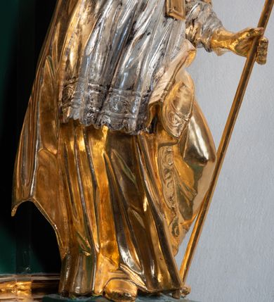 Zdjęcie nr 22: Ołtarz przyścienny, architektoniczny, jednokondygnacyjny, jednoosiowy ze zwieńczeniem. Umieszczony na dwustopniowym, kamiennym podwyższeniu. Mensa prostopadłościenna, z portatylem i współczesnym antepedium ozdobionym postacią św. Weroniki trzymającej chustę z odbiciem twarzy Chrystusa (veraikon) i rzeźbionym ornamentem ze srebrzonych liści i złoconych kiści winogron; tło w kolorze struktury ołtarza. Retabulum na wysokim profilowanym, dwustopniowym cokole, flankowane zwielokrotnionymi pilastrami z jońskimi kapitelami. Pilastry dźwigają przerwane belkowanie z wydatnym profilowanym gzymsem z przerwanym przyczółkiem. Zwieńczenie o wklęsłych bokach ujęte spływami wolutowymi dźwigającymi gzyms w formie nadwieszonego łuku odcinkowego. Na tle pilastrów ustawione na profilowanych impostach rzeźby: po prawej stronie św. Wojciecha, po lewej św. Stanisława. Na przyczółkach znajdują się siedzące putta. Pole środkowe o kształcie prostokąta stojącego od góry zamkniętego łukiem półkolistym nadwieszonym, w kluczu ornament z motywu rocaille. Wewnątrz pola ujęty profilowaną, złoconą ramą obraz z przedstawieniem św. Mikołaja z Miry. W zwieńczeniu obraz w ramie z wklęsłymi bokami i wypukłymi dolną i górną krawędzią przedstawiający św. Marię Magdalenę. Nastawę ujmują ornamentalne uszy, utworzone z motywów rocaille'owych i liściasto-kwiatowych zwisów. Na kapitele są nałożone rocaille'owe kartusze, a pod nimi podwieszone zwisające ulistnione i ukwiecone gałązki wzbogacone motywami rocaille'ów. Struktura ołtarza polichromowana w kolorze ciemnozielonym. Bazy pilastrów, kapitele, uszy, ornamenty, profilowania, obramienia płycin i ramy obrazów złocone. Rzeźby świętych złocone, srebrzone i polichromowane. Rzeźby aniołków złocone i polichromowane.

