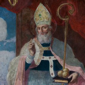 Zdjęcie nr 1: Obraz w kształcie stojącego prostokąta zamkniętego od góry półkolistym łukiem, nadwieszonym, w profilowanej, złoconej ramie ozdobionej motywem muszli w połowie długości dłuższych boków. Został umieszczony w polu środkowym ołtarza bocznego prawego. Postać św. Mikołaja ukazana w pozycji stojącej, frontalnie, we wnętrzu na tle upiętej ciemnoczerwonej draperii. Głowa świętego przechylona nieznacznie w prawo. Twarz owalna, okolona długą, siwą brodą. Oczy duże, głęboko osadzone, wzrok skierowany na wprost. Nos wydatny, prosty, usta zaczerwienione. Na głowie złota infuła, ozdobiona kwadratowym zielonym kamieniem szlachetnym. Wokół głowy nimb. Święty unosi prawą rękę w geście błogosławieństwa, w lewej ręce, o którą oparty jest pastorał, trzyma księgę, z leżącymi na niej trzema złotymi kulami. Ubrany jest w granatową sutannę i białą komżę, układającą się w drobne płytkie fałdy. Na piersi ma paliusz, a na ramionach kapę w kolorze szarym o różowej podszewce. Z lewej strony obrazu okno, w nim widoczny pejzaż z rzeką. Nad rzeką most, przy nim św. Mikołaj wręczający trzem pannom sakiewki z posagiem. Na brzegu rzeki łódź, w głębi widoczny zarys architektury, drzewa i zarysy wzgórz, ponad którymi na błękitnym niebie kłębią się białe chmury. Po prawej stronie obrazu stolik nakryty ciemnobłękitną tkaniną, na nim taca z kwiatami, różańcem i figurką. Kolorystyka obrazu stonowana z silnym akcentem bieli komży i różu podszewki płaszcza.
