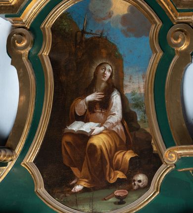 Zdjęcie nr 4: Obraz przedstawiający św. Marię Magdalenę ujęty w profilowaną ramę o fantazyjnym kształcie. W centrum kompozycji pokutująca Maria Magdalena ukazana całopostaciowo, w pozycji siedzącej, zwrócona w trzech czwartych do widza. Głowa świętej uniesiona, przechylona na lewe ramię. Twarz owalna, oczy okrągłe, przymknięte, wzrok skierowany ku górze. Nos prosty, wyraźnie zaznaczony, usta małe o pełnych wargach. Długie jasnobrązowe włosy swobodnie opadające na ramiona i piersi. Wokół głowy promienisty nimb. Prawa ręka złożona na piersi, lewa podtrzymuje leżącą na kolanach otwartą księgę. Święta jest ubrana w białą, przepasaną w stanie suknię i żółty płaszcz przewieszony przez prawe ramię i okrywający kolana. Fałdy płaszcza układają się miękko, tkanina podkreśla kształt ciała. Spod płaszcza wystają nagie stopy, lewa bardziej wysunięta do przodu. Z prawej strony obrazu, u stóp świętej leżą czaszka, dyscyplina i naczynie w kształcie pucharu. Święta ukazana na tle wysokiego skalistego zbocza, na którym widoczne połamane, uschnięte drzewa. Po prawej stronie w głębi obrazu, zza skały widoczny pejzaż. Ponad skałą błękitne niebo, na nim skłębione, ciemne chmury, spomiędzy których wyłania się słońce. 
Kompozycja obrazu statyczna. Kolorystyka stonowana, nasycona, w odcieniach brązu i ochry. Wyraźne akcenty kolorystyczne tworzą biel księgi i rękaw sukni w centrum obrazu, żółcień płaszcza i błękit nieba.
