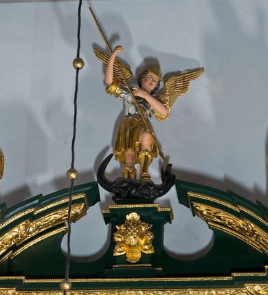 Zdjęcie nr 45: Ołtarz ustawiony na kamiennym podwyższeniu, przyścienny, architektoniczny, jednoosiowy, dwukondygnacyjny ze zwieńczeniem. Podstawa ołtarza skrzyniowa, na niej kamienna mensa z centralnie umieszczonym portatylem. Antepedium późne (secesyjne), datowane na odwrocie „1914”, ozdobione figurą anioła trzymającego wstęgę z napisem „AVE MARIA” i rzeźbionym ornamentem ze złoconych liści winogron i srebrzonych lilii. Retabulum jest flankowane dwiema parami ustawionych uskokowo i osadzonych na wysokich cokołach kolumn kompozytowych, ozdobionych główkami aniołków ujętych dekoracją małżowinową. Kolumny dźwigają belkowanie z wydatnym, przełamującym się gzymsem ozdobionym ornamentem małżowinowym. Nad belkowaniem trójkątny przyczółek z rzeźbioną figurą Boga Ojca w polu tympanonu i figurami aniołów na jego bokach. Druga kondygnacja ołtarza jest flankowana pojedynczymi kolumienkami i kanelowanymi pilasterkami korynckimi, ustawionymi na wysokich cokołach. Boki ozdobione uszami w kształcie małżowiny. Na zewnątrz kolumn, na osiach kolumn zewnętrznych niższej kondygnacji, ustawione na impostach figury: św. Kazimierza po lewej stronie, św. Stanisława po prawej. Kolumny podpierają belkowanie z przełamującym się gzymsem ozdobionym ornamentem małżowinowym, ponad którym zwieńczenie w formie przyczółka odcinkowego przerwanego. Łuk przyczółka profilowany z uskokami, dekorowany ornamentem małżowinowym. Pośrodku zwieńczenia, w przerwanym przyczółku rzeźba św. Michała Archanioła, ustawiona na wysokim cokole z dekoracją w formie bukietu granatów otoczonych liśćmi akantu. Po bokach, na osiach kolumn rzeźbione figury: św. Barbary po lewej stronie i św. Jana Chrzciciela po stronie prawej. Pomiędzy impostami kolumn, w predelli profilowana płycina w kształcie leżącego prostokąta z wyciętymi uskokowo górnymi narożnikami. W niej obraz olejny na płótnie (przyklejony do struktury) ze sceną Nawiedzenia św. Elżbiety. W polu środkowym pierwszej kondygnacji obraz z przedstawieniem Najświętszego Serca Pana Jezusa w profilowanej ramie w kształcie stojącego prostokąta, ozdobionej ornamentem małżowinowym. W drugiej kondygnacji  pole środkowe w kształcie prostokąta leżącego (zbliżonego do kwadratu), obwiedzione frezowaną ramką, z wpisaną w nią ramą o kształcie oktagonalnym, profilowaną i ozdobioną ornamentem małżowinowym, z obrazem przedstawiającym św. Antoniego. Strukturę retabulum, a także prostokątne płyciny zdobiące cokoły i tło kolumn, podkreślają frezowane ramki. Kolumny, pilastry, kapitele, ornamenty, obramienia płycin i belkowania, frezowane ramki złocone. Ramy obrazów złocone i polichromowane. Rzeźby złocone, srebrzone i polichromowane. 