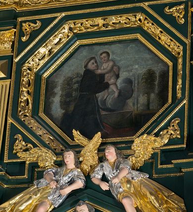 Zdjęcie nr 56: Ołtarz ustawiony na kamiennym podwyższeniu, przyścienny, architektoniczny, jednoosiowy, dwukondygnacyjny ze zwieńczeniem. Podstawa ołtarza skrzyniowa, na niej kamienna mensa z centralnie umieszczonym portatylem. Antepedium późne (secesyjne), datowane na odwrocie „1914”, ozdobione figurą anioła trzymającego wstęgę z napisem „AVE MARIA” i rzeźbionym ornamentem ze złoconych liści winogron i srebrzonych lilii. Retabulum jest flankowane dwiema parami ustawionych uskokowo i osadzonych na wysokich cokołach kolumn kompozytowych, ozdobionych główkami aniołków ujętych dekoracją małżowinową. Kolumny dźwigają belkowanie z wydatnym, przełamującym się gzymsem ozdobionym ornamentem małżowinowym. Nad belkowaniem trójkątny przyczółek z rzeźbioną figurą Boga Ojca w polu tympanonu i figurami aniołów na jego bokach. Druga kondygnacja ołtarza jest flankowana pojedynczymi kolumienkami i kanelowanymi pilasterkami korynckimi, ustawionymi na wysokich cokołach. Boki ozdobione uszami w kształcie małżowiny. Na zewnątrz kolumn, na osiach kolumn zewnętrznych niższej kondygnacji, ustawione na impostach figury: św. Kazimierza po lewej stronie, św. Stanisława po prawej. Kolumny podpierają belkowanie z przełamującym się gzymsem ozdobionym ornamentem małżowinowym, ponad którym zwieńczenie w formie przyczółka odcinkowego przerwanego. Łuk przyczółka profilowany z uskokami, dekorowany ornamentem małżowinowym. Pośrodku zwieńczenia, w przerwanym przyczółku rzeźba św. Michała Archanioła, ustawiona na wysokim cokole z dekoracją w formie bukietu granatów otoczonych liśćmi akantu. Po bokach, na osiach kolumn rzeźbione figury: św. Barbary po lewej stronie i św. Jana Chrzciciela po stronie prawej. Pomiędzy impostami kolumn, w predelli profilowana płycina w kształcie leżącego prostokąta z wyciętymi uskokowo górnymi narożnikami. W niej obraz olejny na płótnie (przyklejony do struktury) ze sceną Nawiedzenia św. Elżbiety. W polu środkowym pierwszej kondygnacji obraz z przedstawieniem Najświętszego Serca Pana Jezusa w profilowanej ramie w kształcie stojącego prostokąta, ozdobionej ornamentem małżowinowym. W drugiej kondygnacji  pole środkowe w kształcie prostokąta leżącego (zbliżonego do kwadratu), obwiedzione frezowaną ramką, z wpisaną w nią ramą o kształcie oktagonalnym, profilowaną i ozdobioną ornamentem małżowinowym, z obrazem przedstawiającym św. Antoniego. Strukturę retabulum, a także prostokątne płyciny zdobiące cokoły i tło kolumn, podkreślają frezowane ramki. Kolumny, pilastry, kapitele, ornamenty, obramienia płycin i belkowania, frezowane ramki złocone. Ramy obrazów złocone i polichromowane. Rzeźby złocone, srebrzone i polichromowane. 