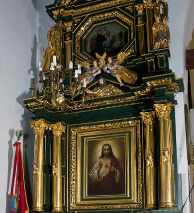Zdjęcie nr 2: Ołtarz ustawiony na kamiennym podwyższeniu, przyścienny, architektoniczny, jednoosiowy, dwukondygnacyjny ze zwieńczeniem. Podstawa ołtarza skrzyniowa, na niej kamienna mensa z centralnie umieszczonym portatylem. Antepedium późne (secesyjne), datowane na odwrocie „1914”, ozdobione figurą anioła trzymającego wstęgę z napisem „AVE MARIA” i rzeźbionym ornamentem ze złoconych liści winogron i srebrzonych lilii. Retabulum jest flankowane dwiema parami ustawionych uskokowo i osadzonych na wysokich cokołach kolumn kompozytowych, ozdobionych główkami aniołków ujętych dekoracją małżowinową. Kolumny dźwigają belkowanie z wydatnym, przełamującym się gzymsem ozdobionym ornamentem małżowinowym. Nad belkowaniem trójkątny przyczółek z rzeźbioną figurą Boga Ojca w polu tympanonu i figurami aniołów na jego bokach. Druga kondygnacja ołtarza jest flankowana pojedynczymi kolumienkami i kanelowanymi pilasterkami korynckimi, ustawionymi na wysokich cokołach. Boki ozdobione uszami w kształcie małżowiny. Na zewnątrz kolumn, na osiach kolumn zewnętrznych niższej kondygnacji, ustawione na impostach figury: św. Kazimierza po lewej stronie, św. Stanisława po prawej. Kolumny podpierają belkowanie z przełamującym się gzymsem ozdobionym ornamentem małżowinowym, ponad którym zwieńczenie w formie przyczółka odcinkowego przerwanego. Łuk przyczółka profilowany z uskokami, dekorowany ornamentem małżowinowym. Pośrodku zwieńczenia, w przerwanym przyczółku rzeźba św. Michała Archanioła, ustawiona na wysokim cokole z dekoracją w formie bukietu granatów otoczonych liśćmi akantu. Po bokach, na osiach kolumn rzeźbione figury: św. Barbary po lewej stronie i św. Jana Chrzciciela po stronie prawej. Pomiędzy impostami kolumn, w predelli profilowana płycina w kształcie leżącego prostokąta z wyciętymi uskokowo górnymi narożnikami. W niej obraz olejny na płótnie (przyklejony do struktury) ze sceną Nawiedzenia św. Elżbiety. W polu środkowym pierwszej kondygnacji obraz z przedstawieniem Najświętszego Serca Pana Jezusa w profilowanej ramie w kształcie stojącego prostokąta, ozdobionej ornamentem małżowinowym. W drugiej kondygnacji  pole środkowe w kształcie prostokąta leżącego (zbliżonego do kwadratu), obwiedzione frezowaną ramką, z wpisaną w nią ramą o kształcie oktagonalnym, profilowaną i ozdobioną ornamentem małżowinowym, z obrazem przedstawiającym św. Antoniego. Strukturę retabulum, a także prostokątne płyciny zdobiące cokoły i tło kolumn, podkreślają frezowane ramki. Kolumny, pilastry, kapitele, ornamenty, obramienia płycin i belkowania, frezowane ramki złocone. Ramy obrazów złocone i polichromowane. Rzeźby złocone, srebrzone i polichromowane. 