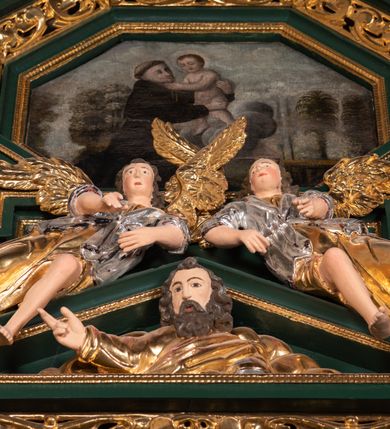 Zdjęcie nr 67: Ołtarz ustawiony na kamiennym podwyższeniu, przyścienny, architektoniczny, jednoosiowy, dwukondygnacyjny ze zwieńczeniem. Podstawa ołtarza skrzyniowa, na niej kamienna mensa z centralnie umieszczonym portatylem. Antepedium późne (secesyjne), datowane na odwrocie „1914”, ozdobione figurą anioła trzymającego wstęgę z napisem „AVE MARIA” i rzeźbionym ornamentem ze złoconych liści winogron i srebrzonych lilii. Retabulum jest flankowane dwiema parami ustawionych uskokowo i osadzonych na wysokich cokołach kolumn kompozytowych, ozdobionych główkami aniołków ujętych dekoracją małżowinową. Kolumny dźwigają belkowanie z wydatnym, przełamującym się gzymsem ozdobionym ornamentem małżowinowym. Nad belkowaniem trójkątny przyczółek z rzeźbioną figurą Boga Ojca w polu tympanonu i figurami aniołów na jego bokach. Druga kondygnacja ołtarza jest flankowana pojedynczymi kolumienkami i kanelowanymi pilasterkami korynckimi, ustawionymi na wysokich cokołach. Boki ozdobione uszami w kształcie małżowiny. Na zewnątrz kolumn, na osiach kolumn zewnętrznych niższej kondygnacji, ustawione na impostach figury: św. Kazimierza po lewej stronie, św. Stanisława po prawej. Kolumny podpierają belkowanie z przełamującym się gzymsem ozdobionym ornamentem małżowinowym, ponad którym zwieńczenie w formie przyczółka odcinkowego przerwanego. Łuk przyczółka profilowany z uskokami, dekorowany ornamentem małżowinowym. Pośrodku zwieńczenia, w przerwanym przyczółku rzeźba św. Michała Archanioła, ustawiona na wysokim cokole z dekoracją w formie bukietu granatów otoczonych liśćmi akantu. Po bokach, na osiach kolumn rzeźbione figury: św. Barbary po lewej stronie i św. Jana Chrzciciela po stronie prawej. Pomiędzy impostami kolumn, w predelli profilowana płycina w kształcie leżącego prostokąta z wyciętymi uskokowo górnymi narożnikami. W niej obraz olejny na płótnie (przyklejony do struktury) ze sceną Nawiedzenia św. Elżbiety. W polu środkowym pierwszej kondygnacji obraz z przedstawieniem Najświętszego Serca Pana Jezusa w profilowanej ramie w kształcie stojącego prostokąta, ozdobionej ornamentem małżowinowym. W drugiej kondygnacji  pole środkowe w kształcie prostokąta leżącego (zbliżonego do kwadratu), obwiedzione frezowaną ramką, z wpisaną w nią ramą o kształcie oktagonalnym, profilowaną i ozdobioną ornamentem małżowinowym, z obrazem przedstawiającym św. Antoniego. Strukturę retabulum, a także prostokątne płyciny zdobiące cokoły i tło kolumn, podkreślają frezowane ramki. Kolumny, pilastry, kapitele, ornamenty, obramienia płycin i belkowania, frezowane ramki złocone. Ramy obrazów złocone i polichromowane. Rzeźby złocone, srebrzone i polichromowane. 