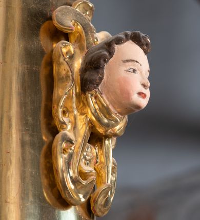 Zdjęcie nr 70: Ołtarz ustawiony na kamiennym podwyższeniu, przyścienny, architektoniczny, jednoosiowy, dwukondygnacyjny ze zwieńczeniem. Podstawa ołtarza skrzyniowa, na niej kamienna mensa z centralnie umieszczonym portatylem. Antepedium późne (secesyjne), datowane na odwrocie „1914”, ozdobione figurą anioła trzymającego wstęgę z napisem „AVE MARIA” i rzeźbionym ornamentem ze złoconych liści winogron i srebrzonych lilii. Retabulum jest flankowane dwiema parami ustawionych uskokowo i osadzonych na wysokich cokołach kolumn kompozytowych, ozdobionych główkami aniołków ujętych dekoracją małżowinową. Kolumny dźwigają belkowanie z wydatnym, przełamującym się gzymsem ozdobionym ornamentem małżowinowym. Nad belkowaniem trójkątny przyczółek z rzeźbioną figurą Boga Ojca w polu tympanonu i figurami aniołów na jego bokach. Druga kondygnacja ołtarza jest flankowana pojedynczymi kolumienkami i kanelowanymi pilasterkami korynckimi, ustawionymi na wysokich cokołach. Boki ozdobione uszami w kształcie małżowiny. Na zewnątrz kolumn, na osiach kolumn zewnętrznych niższej kondygnacji, ustawione na impostach figury: św. Kazimierza po lewej stronie, św. Stanisława po prawej. Kolumny podpierają belkowanie z przełamującym się gzymsem ozdobionym ornamentem małżowinowym, ponad którym zwieńczenie w formie przyczółka odcinkowego przerwanego. Łuk przyczółka profilowany z uskokami, dekorowany ornamentem małżowinowym. Pośrodku zwieńczenia, w przerwanym przyczółku rzeźba św. Michała Archanioła, ustawiona na wysokim cokole z dekoracją w formie bukietu granatów otoczonych liśćmi akantu. Po bokach, na osiach kolumn rzeźbione figury: św. Barbary po lewej stronie i św. Jana Chrzciciela po stronie prawej. Pomiędzy impostami kolumn, w predelli profilowana płycina w kształcie leżącego prostokąta z wyciętymi uskokowo górnymi narożnikami. W niej obraz olejny na płótnie (przyklejony do struktury) ze sceną Nawiedzenia św. Elżbiety. W polu środkowym pierwszej kondygnacji obraz z przedstawieniem Najświętszego Serca Pana Jezusa w profilowanej ramie w kształcie stojącego prostokąta, ozdobionej ornamentem małżowinowym. W drugiej kondygnacji  pole środkowe w kształcie prostokąta leżącego (zbliżonego do kwadratu), obwiedzione frezowaną ramką, z wpisaną w nią ramą o kształcie oktagonalnym, profilowaną i ozdobioną ornamentem małżowinowym, z obrazem przedstawiającym św. Antoniego. Strukturę retabulum, a także prostokątne płyciny zdobiące cokoły i tło kolumn, podkreślają frezowane ramki. Kolumny, pilastry, kapitele, ornamenty, obramienia płycin i belkowania, frezowane ramki złocone. Ramy obrazów złocone i polichromowane. Rzeźby złocone, srebrzone i polichromowane. 