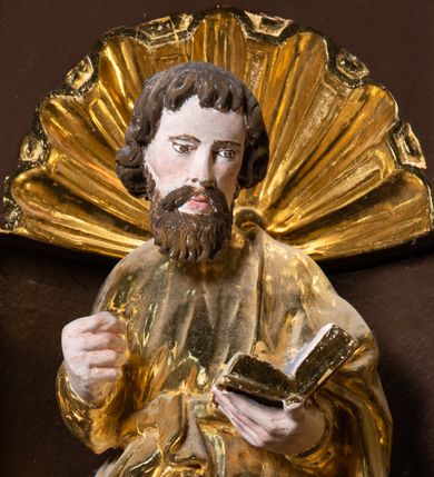 Zdjęcie nr 24: Ambona drewniana, przyścienna, wisząca, dostawiona do północnej ściany nawy ze schodkami biegnącymi wzdłuż ściany. Kosz ambony jest sześcioboczny, z niewielkim parapetem. Jego boki zostały podzielone na pola stojącymi na wysokich cokołach pięcioma kolumienkami o korynckich kapitelach, dźwigających profilowane belkowanie. W polach prostokątne płyciny z konchowymi wnękami ozdobionymi muszlami z figurami ewangelistów. 
We wnękach rzeźby z przedstawieniami ewangelistów i Chrystusa. Figury drewniane pełnoplastyczne, wydrążone od tyłu, polichromowane, złocone i srebrzone, ustawione na niewielkich prostokątnych podstawach, od lewej: św. Łukasz wsparty prawą nogą na głowie byka, św. Marek wsparty prawą nogą na głowie lwa, św. Jan z orłem przy prawej nodze, Chrystus Salvator Mundi, św. Mateusz z aniołem przy prawej nodze. Ewangeliści trzymają w prawych dłoniach otwarte księgi, z wyjątkiem św. Mateusza, trzymającego kodeks w lewej ręce. Dłonie ewangelistów nieproporcjonalnie duże. Szaty bogato pofałdowane, głęboko cięte. 
Podstawa kosza bogato profilowana, ozdobiona podwieszoną dekoracyjną szyszką. Schodki ograniczone parapetem z trzema romboidalnymi płycinami w złoconych profilowanych obramieniach. Na filarze przy wejściu na schodki złocona kula z szyszką. Zaplecek w kształcie stojącego prostokąta, w górnej części ujęty zwężającymi się ku dołowi pilastrami wypełnionymi cekinami, zwieńczonymi rombowymi wypustkami i korynckimi kapitelami, które podtrzymują przełamujące się nad nimi belkowanie. Pośrodku zaplecka w prostokątnym obramieniu zamkniętym nadwieszonym łukiem półkolistym płaskorzeźbione popiersie Boga Ojca wyłaniającego się z obłoków. Prawa ręka Boga wzniesiona w geście błogosławieństwa, lewa oparta na globie ziemskim zwieńczonym krzyżem. Tłem dla postaci Boga Ojca jest rozwiana poła płaszcza układająca się niemal półkoliście. Baldachim ośmioboczny. W profilowanym podniebiu, ozdobionym pasem ornamentu małżowinowo-chrząstkowego i profilowanymi wisiorami, gołębica Ducha Świętego na tle glorii utworzonej z prostych promieni o równej długości. Baldachim ozdobiony zamkniętą koroną, którą tworzy pięć esownic pokrytych pasami ornamentu małżowinowo-chrząstkowego. W zwieńczeniu pełnoplastyczna rzeźba przedstawiająca św. Jana Chrzciciela. Figura drewniana, wydrążona z tyłu, polichromowana, złocona i srebrzona, ustawiona na niewielkiej wielobocznej profilowanej podstawie. Święty w prawej ręce trzyma wysoki krzyż, w lewej księgę, na której spoczywa Baranek Boży. Struktura ambony ciemnobrązowa. Kolumny, kapitele, pilastry w zaplecku korona baldachimu, profilowania i ornamenty złocone, z wyjątkiem srebrzonej ramy w zaplecku i gołębicy Ducha Świętego.