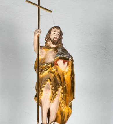 Zdjęcie nr 3: Ambona drewniana, przyścienna, wisząca, dostawiona do północnej ściany nawy ze schodkami biegnącymi wzdłuż ściany. Kosz ambony jest sześcioboczny, z niewielkim parapetem. Jego boki zostały podzielone na pola stojącymi na wysokich cokołach pięcioma kolumienkami o korynckich kapitelach, dźwigających profilowane belkowanie. W polach prostokątne płyciny z konchowymi wnękami ozdobionymi muszlami z figurami ewangelistów. 
We wnękach rzeźby z przedstawieniami ewangelistów i Chrystusa. Figury drewniane pełnoplastyczne, wydrążone od tyłu, polichromowane, złocone i srebrzone, ustawione na niewielkich prostokątnych podstawach, od lewej: św. Łukasz wsparty prawą nogą na głowie byka, św. Marek wsparty prawą nogą na głowie lwa, św. Jan z orłem przy prawej nodze, Chrystus Salvator Mundi, św. Mateusz z aniołem przy prawej nodze. Ewangeliści trzymają w prawych dłoniach otwarte księgi, z wyjątkiem św. Mateusza, trzymającego kodeks w lewej ręce. Dłonie ewangelistów nieproporcjonalnie duże. Szaty bogato pofałdowane, głęboko cięte. 
Podstawa kosza bogato profilowana, ozdobiona podwieszoną dekoracyjną szyszką. Schodki ograniczone parapetem z trzema romboidalnymi płycinami w złoconych profilowanych obramieniach. Na filarze przy wejściu na schodki złocona kula z szyszką. Zaplecek w kształcie stojącego prostokąta, w górnej części ujęty zwężającymi się ku dołowi pilastrami wypełnionymi cekinami, zwieńczonymi rombowymi wypustkami i korynckimi kapitelami, które podtrzymują przełamujące się nad nimi belkowanie. Pośrodku zaplecka w prostokątnym obramieniu zamkniętym nadwieszonym łukiem półkolistym płaskorzeźbione popiersie Boga Ojca wyłaniającego się z obłoków. Prawa ręka Boga wzniesiona w geście błogosławieństwa, lewa oparta na globie ziemskim zwieńczonym krzyżem. Tłem dla postaci Boga Ojca jest rozwiana poła płaszcza układająca się niemal półkoliście. Baldachim ośmioboczny. W profilowanym podniebiu, ozdobionym pasem ornamentu małżowinowo-chrząstkowego i profilowanymi wisiorami, gołębica Ducha Świętego na tle glorii utworzonej z prostych promieni o równej długości. Baldachim ozdobiony zamkniętą koroną, którą tworzy pięć esownic pokrytych pasami ornamentu małżowinowo-chrząstkowego. W zwieńczeniu pełnoplastyczna rzeźba przedstawiająca św. Jana Chrzciciela. Figura drewniana, wydrążona z tyłu, polichromowana, złocona i srebrzona, ustawiona na niewielkiej wielobocznej profilowanej podstawie. Święty w prawej ręce trzyma wysoki krzyż, w lewej księgę, na której spoczywa Baranek Boży. Struktura ambony ciemnobrązowa. Kolumny, kapitele, pilastry w zaplecku korona baldachimu, profilowania i ornamenty złocone, z wyjątkiem srebrzonej ramy w zaplecku i gołębicy Ducha Świętego.