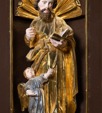 Zdjęcie nr 6: Ambona drewniana, przyścienna, wisząca, dostawiona do północnej ściany nawy ze schodkami biegnącymi wzdłuż ściany. Kosz ambony jest sześcioboczny, z niewielkim parapetem. Jego boki zostały podzielone na pola stojącymi na wysokich cokołach pięcioma kolumienkami o korynckich kapitelach, dźwigających profilowane belkowanie. W polach prostokątne płyciny z konchowymi wnękami ozdobionymi muszlami z figurami ewangelistów. 
We wnękach rzeźby z przedstawieniami ewangelistów i Chrystusa. Figury drewniane pełnoplastyczne, wydrążone od tyłu, polichromowane, złocone i srebrzone, ustawione na niewielkich prostokątnych podstawach, od lewej: św. Łukasz wsparty prawą nogą na głowie byka, św. Marek wsparty prawą nogą na głowie lwa, św. Jan z orłem przy prawej nodze, Chrystus Salvator Mundi, św. Mateusz z aniołem przy prawej nodze. Ewangeliści trzymają w prawych dłoniach otwarte księgi, z wyjątkiem św. Mateusza, trzymającego kodeks w lewej ręce. Dłonie ewangelistów nieproporcjonalnie duże. Szaty bogato pofałdowane, głęboko cięte. 
Podstawa kosza bogato profilowana, ozdobiona podwieszoną dekoracyjną szyszką. Schodki ograniczone parapetem z trzema romboidalnymi płycinami w złoconych profilowanych obramieniach. Na filarze przy wejściu na schodki złocona kula z szyszką. Zaplecek w kształcie stojącego prostokąta, w górnej części ujęty zwężającymi się ku dołowi pilastrami wypełnionymi cekinami, zwieńczonymi rombowymi wypustkami i korynckimi kapitelami, które podtrzymują przełamujące się nad nimi belkowanie. Pośrodku zaplecka w prostokątnym obramieniu zamkniętym nadwieszonym łukiem półkolistym płaskorzeźbione popiersie Boga Ojca wyłaniającego się z obłoków. Prawa ręka Boga wzniesiona w geście błogosławieństwa, lewa oparta na globie ziemskim zwieńczonym krzyżem. Tłem dla postaci Boga Ojca jest rozwiana poła płaszcza układająca się niemal półkoliście. Baldachim ośmioboczny. W profilowanym podniebiu, ozdobionym pasem ornamentu małżowinowo-chrząstkowego i profilowanymi wisiorami, gołębica Ducha Świętego na tle glorii utworzonej z prostych promieni o równej długości. Baldachim ozdobiony zamkniętą koroną, którą tworzy pięć esownic pokrytych pasami ornamentu małżowinowo-chrząstkowego. W zwieńczeniu pełnoplastyczna rzeźba przedstawiająca św. Jana Chrzciciela. Figura drewniana, wydrążona z tyłu, polichromowana, złocona i srebrzona, ustawiona na niewielkiej wielobocznej profilowanej podstawie. Święty w prawej ręce trzyma wysoki krzyż, w lewej księgę, na której spoczywa Baranek Boży. Struktura ambony ciemnobrązowa. Kolumny, kapitele, pilastry w zaplecku korona baldachimu, profilowania i ornamenty złocone, z wyjątkiem srebrzonej ramy w zaplecku i gołębicy Ducha Świętego.
