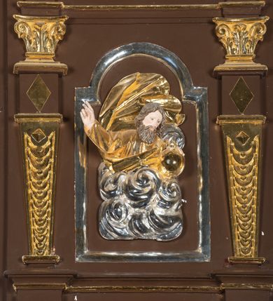 Zdjęcie nr 7: Ambona drewniana, przyścienna, wisząca, dostawiona do północnej ściany nawy ze schodkami biegnącymi wzdłuż ściany. Kosz ambony jest sześcioboczny, z niewielkim parapetem. Jego boki zostały podzielone na pola stojącymi na wysokich cokołach pięcioma kolumienkami o korynckich kapitelach, dźwigających profilowane belkowanie. W polach prostokątne płyciny z konchowymi wnękami ozdobionymi muszlami z figurami ewangelistów. 
We wnękach rzeźby z przedstawieniami ewangelistów i Chrystusa. Figury drewniane pełnoplastyczne, wydrążone od tyłu, polichromowane, złocone i srebrzone, ustawione na niewielkich prostokątnych podstawach, od lewej: św. Łukasz wsparty prawą nogą na głowie byka, św. Marek wsparty prawą nogą na głowie lwa, św. Jan z orłem przy prawej nodze, Chrystus Salvator Mundi, św. Mateusz z aniołem przy prawej nodze. Ewangeliści trzymają w prawych dłoniach otwarte księgi, z wyjątkiem św. Mateusza, trzymającego kodeks w lewej ręce. Dłonie ewangelistów nieproporcjonalnie duże. Szaty bogato pofałdowane, głęboko cięte. 
Podstawa kosza bogato profilowana, ozdobiona podwieszoną dekoracyjną szyszką. Schodki ograniczone parapetem z trzema romboidalnymi płycinami w złoconych profilowanych obramieniach. Na filarze przy wejściu na schodki złocona kula z szyszką. Zaplecek w kształcie stojącego prostokąta, w górnej części ujęty zwężającymi się ku dołowi pilastrami wypełnionymi cekinami, zwieńczonymi rombowymi wypustkami i korynckimi kapitelami, które podtrzymują przełamujące się nad nimi belkowanie. Pośrodku zaplecka w prostokątnym obramieniu zamkniętym nadwieszonym łukiem półkolistym płaskorzeźbione popiersie Boga Ojca wyłaniającego się z obłoków. Prawa ręka Boga wzniesiona w geście błogosławieństwa, lewa oparta na globie ziemskim zwieńczonym krzyżem. Tłem dla postaci Boga Ojca jest rozwiana poła płaszcza układająca się niemal półkoliście. Baldachim ośmioboczny. W profilowanym podniebiu, ozdobionym pasem ornamentu małżowinowo-chrząstkowego i profilowanymi wisiorami, gołębica Ducha Świętego na tle glorii utworzonej z prostych promieni o równej długości. Baldachim ozdobiony zamkniętą koroną, którą tworzy pięć esownic pokrytych pasami ornamentu małżowinowo-chrząstkowego. W zwieńczeniu pełnoplastyczna rzeźba przedstawiająca św. Jana Chrzciciela. Figura drewniana, wydrążona z tyłu, polichromowana, złocona i srebrzona, ustawiona na niewielkiej wielobocznej profilowanej podstawie. Święty w prawej ręce trzyma wysoki krzyż, w lewej księgę, na której spoczywa Baranek Boży. Struktura ambony ciemnobrązowa. Kolumny, kapitele, pilastry w zaplecku korona baldachimu, profilowania i ornamenty złocone, z wyjątkiem srebrzonej ramy w zaplecku i gołębicy Ducha Świętego.