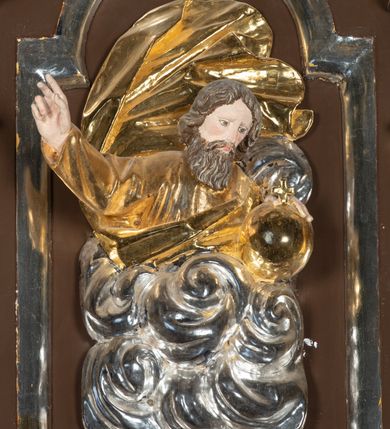 Zdjęcie nr 9: Ambona drewniana, przyścienna, wisząca, dostawiona do północnej ściany nawy ze schodkami biegnącymi wzdłuż ściany. Kosz ambony jest sześcioboczny, z niewielkim parapetem. Jego boki zostały podzielone na pola stojącymi na wysokich cokołach pięcioma kolumienkami o korynckich kapitelach, dźwigających profilowane belkowanie. W polach prostokątne płyciny z konchowymi wnękami ozdobionymi muszlami z figurami ewangelistów. 
We wnękach rzeźby z przedstawieniami ewangelistów i Chrystusa. Figury drewniane pełnoplastyczne, wydrążone od tyłu, polichromowane, złocone i srebrzone, ustawione na niewielkich prostokątnych podstawach, od lewej: św. Łukasz wsparty prawą nogą na głowie byka, św. Marek wsparty prawą nogą na głowie lwa, św. Jan z orłem przy prawej nodze, Chrystus Salvator Mundi, św. Mateusz z aniołem przy prawej nodze. Ewangeliści trzymają w prawych dłoniach otwarte księgi, z wyjątkiem św. Mateusza, trzymającego kodeks w lewej ręce. Dłonie ewangelistów nieproporcjonalnie duże. Szaty bogato pofałdowane, głęboko cięte. 
Podstawa kosza bogato profilowana, ozdobiona podwieszoną dekoracyjną szyszką. Schodki ograniczone parapetem z trzema romboidalnymi płycinami w złoconych profilowanych obramieniach. Na filarze przy wejściu na schodki złocona kula z szyszką. Zaplecek w kształcie stojącego prostokąta, w górnej części ujęty zwężającymi się ku dołowi pilastrami wypełnionymi cekinami, zwieńczonymi rombowymi wypustkami i korynckimi kapitelami, które podtrzymują przełamujące się nad nimi belkowanie. Pośrodku zaplecka w prostokątnym obramieniu zamkniętym nadwieszonym łukiem półkolistym płaskorzeźbione popiersie Boga Ojca wyłaniającego się z obłoków. Prawa ręka Boga wzniesiona w geście błogosławieństwa, lewa oparta na globie ziemskim zwieńczonym krzyżem. Tłem dla postaci Boga Ojca jest rozwiana poła płaszcza układająca się niemal półkoliście. Baldachim ośmioboczny. W profilowanym podniebiu, ozdobionym pasem ornamentu małżowinowo-chrząstkowego i profilowanymi wisiorami, gołębica Ducha Świętego na tle glorii utworzonej z prostych promieni o równej długości. Baldachim ozdobiony zamkniętą koroną, którą tworzy pięć esownic pokrytych pasami ornamentu małżowinowo-chrząstkowego. W zwieńczeniu pełnoplastyczna rzeźba przedstawiająca św. Jana Chrzciciela. Figura drewniana, wydrążona z tyłu, polichromowana, złocona i srebrzona, ustawiona na niewielkiej wielobocznej profilowanej podstawie. Święty w prawej ręce trzyma wysoki krzyż, w lewej księgę, na której spoczywa Baranek Boży. Struktura ambony ciemnobrązowa. Kolumny, kapitele, pilastry w zaplecku korona baldachimu, profilowania i ornamenty złocone, z wyjątkiem srebrzonej ramy w zaplecku i gołębicy Ducha Świętego.