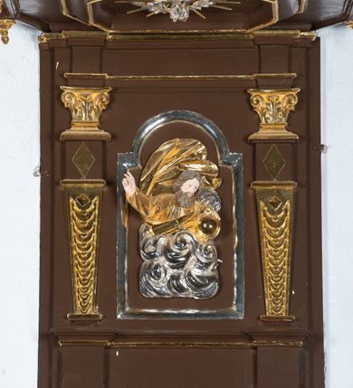 Zdjęcie nr 10: Ambona drewniana, przyścienna, wisząca, dostawiona do północnej ściany nawy ze schodkami biegnącymi wzdłuż ściany. Kosz ambony jest sześcioboczny, z niewielkim parapetem. Jego boki zostały podzielone na pola stojącymi na wysokich cokołach pięcioma kolumienkami o korynckich kapitelach, dźwigających profilowane belkowanie. W polach prostokątne płyciny z konchowymi wnękami ozdobionymi muszlami z figurami ewangelistów. 
We wnękach rzeźby z przedstawieniami ewangelistów i Chrystusa. Figury drewniane pełnoplastyczne, wydrążone od tyłu, polichromowane, złocone i srebrzone, ustawione na niewielkich prostokątnych podstawach, od lewej: św. Łukasz wsparty prawą nogą na głowie byka, św. Marek wsparty prawą nogą na głowie lwa, św. Jan z orłem przy prawej nodze, Chrystus Salvator Mundi, św. Mateusz z aniołem przy prawej nodze. Ewangeliści trzymają w prawych dłoniach otwarte księgi, z wyjątkiem św. Mateusza, trzymającego kodeks w lewej ręce. Dłonie ewangelistów nieproporcjonalnie duże. Szaty bogato pofałdowane, głęboko cięte. 
Podstawa kosza bogato profilowana, ozdobiona podwieszoną dekoracyjną szyszką. Schodki ograniczone parapetem z trzema romboidalnymi płycinami w złoconych profilowanych obramieniach. Na filarze przy wejściu na schodki złocona kula z szyszką. Zaplecek w kształcie stojącego prostokąta, w górnej części ujęty zwężającymi się ku dołowi pilastrami wypełnionymi cekinami, zwieńczonymi rombowymi wypustkami i korynckimi kapitelami, które podtrzymują przełamujące się nad nimi belkowanie. Pośrodku zaplecka w prostokątnym obramieniu zamkniętym nadwieszonym łukiem półkolistym płaskorzeźbione popiersie Boga Ojca wyłaniającego się z obłoków. Prawa ręka Boga wzniesiona w geście błogosławieństwa, lewa oparta na globie ziemskim zwieńczonym krzyżem. Tłem dla postaci Boga Ojca jest rozwiana poła płaszcza układająca się niemal półkoliście. Baldachim ośmioboczny. W profilowanym podniebiu, ozdobionym pasem ornamentu małżowinowo-chrząstkowego i profilowanymi wisiorami, gołębica Ducha Świętego na tle glorii utworzonej z prostych promieni o równej długości. Baldachim ozdobiony zamkniętą koroną, którą tworzy pięć esownic pokrytych pasami ornamentu małżowinowo-chrząstkowego. W zwieńczeniu pełnoplastyczna rzeźba przedstawiająca św. Jana Chrzciciela. Figura drewniana, wydrążona z tyłu, polichromowana, złocona i srebrzona, ustawiona na niewielkiej wielobocznej profilowanej podstawie. Święty w prawej ręce trzyma wysoki krzyż, w lewej księgę, na której spoczywa Baranek Boży. Struktura ambony ciemnobrązowa. Kolumny, kapitele, pilastry w zaplecku korona baldachimu, profilowania i ornamenty złocone, z wyjątkiem srebrzonej ramy w zaplecku i gołębicy Ducha Świętego.