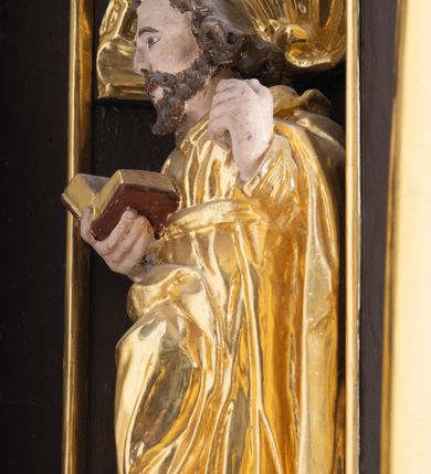 Zdjęcie nr 11: Ambona drewniana, przyścienna, wisząca, dostawiona do północnej ściany nawy ze schodkami biegnącymi wzdłuż ściany. Kosz ambony jest sześcioboczny, z niewielkim parapetem. Jego boki zostały podzielone na pola stojącymi na wysokich cokołach pięcioma kolumienkami o korynckich kapitelach, dźwigających profilowane belkowanie. W polach prostokątne płyciny z konchowymi wnękami ozdobionymi muszlami z figurami ewangelistów. 
We wnękach rzeźby z przedstawieniami ewangelistów i Chrystusa. Figury drewniane pełnoplastyczne, wydrążone od tyłu, polichromowane, złocone i srebrzone, ustawione na niewielkich prostokątnych podstawach, od lewej: św. Łukasz wsparty prawą nogą na głowie byka, św. Marek wsparty prawą nogą na głowie lwa, św. Jan z orłem przy prawej nodze, Chrystus Salvator Mundi, św. Mateusz z aniołem przy prawej nodze. Ewangeliści trzymają w prawych dłoniach otwarte księgi, z wyjątkiem św. Mateusza, trzymającego kodeks w lewej ręce. Dłonie ewangelistów nieproporcjonalnie duże. Szaty bogato pofałdowane, głęboko cięte. 
Podstawa kosza bogato profilowana, ozdobiona podwieszoną dekoracyjną szyszką. Schodki ograniczone parapetem z trzema romboidalnymi płycinami w złoconych profilowanych obramieniach. Na filarze przy wejściu na schodki złocona kula z szyszką. Zaplecek w kształcie stojącego prostokąta, w górnej części ujęty zwężającymi się ku dołowi pilastrami wypełnionymi cekinami, zwieńczonymi rombowymi wypustkami i korynckimi kapitelami, które podtrzymują przełamujące się nad nimi belkowanie. Pośrodku zaplecka w prostokątnym obramieniu zamkniętym nadwieszonym łukiem półkolistym płaskorzeźbione popiersie Boga Ojca wyłaniającego się z obłoków. Prawa ręka Boga wzniesiona w geście błogosławieństwa, lewa oparta na globie ziemskim zwieńczonym krzyżem. Tłem dla postaci Boga Ojca jest rozwiana poła płaszcza układająca się niemal półkoliście. Baldachim ośmioboczny. W profilowanym podniebiu, ozdobionym pasem ornamentu małżowinowo-chrząstkowego i profilowanymi wisiorami, gołębica Ducha Świętego na tle glorii utworzonej z prostych promieni o równej długości. Baldachim ozdobiony zamkniętą koroną, którą tworzy pięć esownic pokrytych pasami ornamentu małżowinowo-chrząstkowego. W zwieńczeniu pełnoplastyczna rzeźba przedstawiająca św. Jana Chrzciciela. Figura drewniana, wydrążona z tyłu, polichromowana, złocona i srebrzona, ustawiona na niewielkiej wielobocznej profilowanej podstawie. Święty w prawej ręce trzyma wysoki krzyż, w lewej księgę, na której spoczywa Baranek Boży. Struktura ambony ciemnobrązowa. Kolumny, kapitele, pilastry w zaplecku korona baldachimu, profilowania i ornamenty złocone, z wyjątkiem srebrzonej ramy w zaplecku i gołębicy Ducha Świętego.