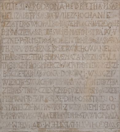 Zdjęcie nr 2: Nagrobek w formie płaskorzeźbionej tablicy o kształcie stojącego prostokąta. W jego górnej części znajduje się wyobrażenie Elżbiety z Giebułtowskich Pisarskiej przedstawionej frontalnie, do pasa. Kobieta jest obramiona półkolistą arkadą utworzoną z kaboszonów. Po bokach arkady dwa ozdobione rollwerkami kartusze z godłami herbów Bersten (po lewej stronie) i Jelita (po prawej stronie). Wyłaniająca się spod szat twarz zmarłej o kształcie sercowatym, z pełnymi policzkami z dużymi zamkniętymi oczami, z prostym, wydatnym nosem, wąskimi ustami i wyraźnie zaznaczonym podbródkiem. Zmarła jest ubrana we wdowi welon (rańtuch) spięty pod brodą i rozchylający się od środka na boki. Gładki welon zdobi jedna rurkowata fałda biegnąca na całej jego długości. Głowę nakrywa czepek, a szyję zasłania podwika. Spódnica spięta pasem z ozdobnymi klamrami, układana w drobne rurkowate fałdy. Ręce złożone, w nich chustka, przez prawą rękę przewieszony różaniec. W dolnej partii nagrobka inskrypcja kuta majuskułą. Treść inskrypcji w otoku bordiury i w polu. Inskrypcja w otoku: Inskrypcja na bordiurze "THU. LIESI. URODZONA. HELZBIETHA. PISARSKA / Z GIEBVLTOWA. KTORA MAIANCZ WIEKU / SWEGO. LIATTH. LVI. S. STHEM. SZWIATHEM. / ROZL/ONCZONA. W ROKV. 1576. XX. DNIA MARCEA." Inskrypcja w polu: "HELIZABET. PISARSKA. TV LIEZY. KOCHANIE. / DZIATEK. SWICH. ALBO. RACZEI. BACZ. I NARZEKANIE / POMNICZIE. NA. POBOŻNE. SWOIEI. MATKI SPRAWY/CZNE POTOMSTWO IAKO I IEI W TIM. BIŁ BOG. ŁASKAWY / THA WAM W BOIZNIE I BOZEJ. WYCHOWANIE DAŁA / THAKOWE. ZE. THAM. ZADNA. ZMAZA. NIEZOSTAŁA / THEGOSZ. I. PO. SMIERCZI. SWEI. VPRZYIMIE WAM. ZICZI. / BISZCIE. TAK. IAKO. ONA. DOKONALI. WSISCZI. / WIEKOW. SWOICH. A W TIM. WAM WĄTPICZ NIEPOTRZEBA. / ZE. WAS. THIM. CZIESICZ. BENDZIE. NAIWISI. BOG. Z NIEBA. / I. TIM. WAM. TO. ZAPLACZI. ZE. DNIA. OSTATNIEGO. / STANIECZIE. NAPRAWICZI. Z WIBRANEMI. IEGO. / BARBARA TOMASOWSKA. TEN. KAMIEŃ. POSTAWICZ. DAŁA". 


