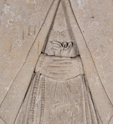 Zdjęcie nr 9: Nagrobek w formie płaskorzeźbionej tablicy o kształcie stojącego prostokąta. W jego górnej części znajduje się wyobrażenie Elżbiety z Giebułtowskich Pisarskiej przedstawionej frontalnie, do pasa. Kobieta jest obramiona półkolistą arkadą utworzoną z kaboszonów. Po bokach arkady dwa ozdobione rollwerkami kartusze z godłami herbów Bersten (po lewej stronie) i Jelita (po prawej stronie). Wyłaniająca się spod szat twarz zmarłej o kształcie sercowatym, z pełnymi policzkami z dużymi zamkniętymi oczami, z prostym, wydatnym nosem, wąskimi ustami i wyraźnie zaznaczonym podbródkiem. Zmarła jest ubrana we wdowi welon (rańtuch) spięty pod brodą i rozchylający się od środka na boki. Gładki welon zdobi jedna rurkowata fałda biegnąca na całej jego długości. Głowę nakrywa czepek, a szyję zasłania podwika. Spódnica spięta pasem z ozdobnymi klamrami, układana w drobne rurkowate fałdy. Ręce złożone, w nich chustka, przez prawą rękę przewieszony różaniec. W dolnej partii nagrobka inskrypcja kuta majuskułą. Treść inskrypcji w otoku bordiury i w polu. Inskrypcja w otoku: Inskrypcja na bordiurze "THU. LIESI. URODZONA. HELZBIETHA. PISARSKA / Z GIEBVLTOWA. KTORA MAIANCZ WIEKU / SWEGO. LIATTH. LVI. S. STHEM. SZWIATHEM. / ROZL/ONCZONA. W ROKV. 1576. XX. DNIA MARCEA." Inskrypcja w polu: "HELIZABET. PISARSKA. TV LIEZY. KOCHANIE. / DZIATEK. SWICH. ALBO. RACZEI. BACZ. I NARZEKANIE / POMNICZIE. NA. POBOŻNE. SWOIEI. MATKI SPRAWY/CZNE POTOMSTWO IAKO I IEI W TIM. BIŁ BOG. ŁASKAWY / THA WAM W BOIZNIE I BOZEJ. WYCHOWANIE DAŁA / THAKOWE. ZE. THAM. ZADNA. ZMAZA. NIEZOSTAŁA / THEGOSZ. I. PO. SMIERCZI. SWEI. VPRZYIMIE WAM. ZICZI. / BISZCIE. TAK. IAKO. ONA. DOKONALI. WSISCZI. / WIEKOW. SWOICH. A W TIM. WAM WĄTPICZ NIEPOTRZEBA. / ZE. WAS. THIM. CZIESICZ. BENDZIE. NAIWISI. BOG. Z NIEBA. / I. TIM. WAM. TO. ZAPLACZI. ZE. DNIA. OSTATNIEGO. / STANIECZIE. NAPRAWICZI. Z WIBRANEMI. IEGO. / BARBARA TOMASOWSKA. TEN. KAMIEŃ. POSTAWICZ. DAŁA". 


