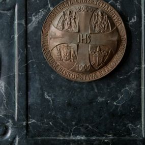 Zdjęcie nr 1: Czara półkolista, gładka, zakończona szerokim profilowanym kołnierzem ujętym od dołu wklęsłą opaską. Zaplecek w kształcie prostokąta zakończonego u góry łukiem odcinkowym, z prostokątną płyciną ujętą ramą w kształcie listwy, u góry otwartą, po bokach ozdobioną wolutowymi spływami. W polu płyciny aplikowany metalowy medalion jubileuszowy z krzyżem, na którym napisy: „IHS” na skrzyżowaniu ramion, „2000” w rozszerzeniu górnej belki, „1000” w rozszerzeniu dolnej belki. W polach pomiędzy ramionami krzyża przedstawienia: u góry (od lewej) św. Jadwiga królowa i św. Stanisław, u dołu (od lewej) herb biskupi kardynała Franciszka Macharskiego i herb papieski Jana Pawła II.  Na otoku napisy: na górnym łuku „JUBILEUSZ CHRZEŚCIJAŃSTWA” na dolnym łuku „MILLENNIUM BISKUPSTWA KRAKOWSKIEGO”.