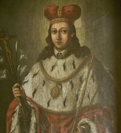 Zdjęcie nr 3: Obraz w kształcie stojącego prostokąta, w szerokiej, drewnianej ramie. Święty jest ukazany frontalnie, do kolan, w pozycji stojącej. Jego głowa jest mała, twarz owalna, oczy duże, okrągłe z wyraźnie zarysowanymi powiekami, wzrok skierowany na widza, nos prosty, usta małe. Twarz jest okolona długimi swobodnie spadającymi na ramiona pofalowanymi włosami. Głowę nakrywa mitra książęca w kolorze czerwonym, ze złotymi kabłąkami wysadzanymi kamieniami. Wokół głowy nieznacznie zaznaczony świetlisty nimb. Święty odziany jest w czerwony płaszcz podbity gronostajami, układający się dwiema pionowymi fałdami wokół wysuwających się spod płaszcza rąk. W prawej ręce trzyma krucyfiks i lilie, w lewej, opuszczonej nieco niżej dzierży berło. Na ramionach gronostajowa peleryna z brzegiem zaznaczonym lamówką i zawieszony na złotym łańcuchu owalny medalion z wizerunkiem Matki Boskiej z Dzieciątkiem, ponad pelerynką widoczny fragment spodniej szaty i kołnierzyk. Tło obrazu jednolite w kolorze brązowo-szarym.