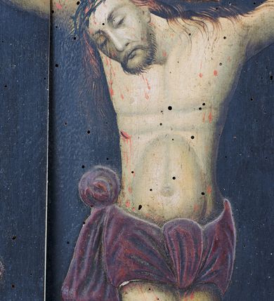 Zdjęcie nr 2: Obraz w kształcie prostokąta stojącego, płaskorzeźbiony i malowany, przedstawiający Chrystusa Ukrzyżowanego. Zbawiciel przybity do krzyża trzema gwoździami, wisi na ramionach, układających się w literę "C". Głowa w cierniowej koronie opada mocno na prawe ramię. Twarz modelowana sumarycznie, oczy zamknięte, nos długi, broda i włosy rzadkie, krótkie. Korpus z zaznaczoną klatką piersiową i linią żeber, z krwawiącą raną na prawym boku. Kolana lekko ugięte, stopy skrzyżowane, prawa założona na lewą, przebite jednym gwoździem. Na całym ciałem ślady krwi. Perizonium przewiązane dwoma węzłami na środku i nad prawym bokiem, z końcem spływającym po biodrze. Nad głową Chrystusa titulus z napisem "INRI". Ponad krzyżem po lewej stronie słońce , po prawej księżyc. W tle widok Jerozolimy za ceglanym murem. Tło, krzyż i perizonium płaskorzeźbione, postać Chrystusa malowana. Obraz ujęty w drewnianą profilowaną ramę ozdobioną wolutowo skręconą wicią roślinną i kimationem.