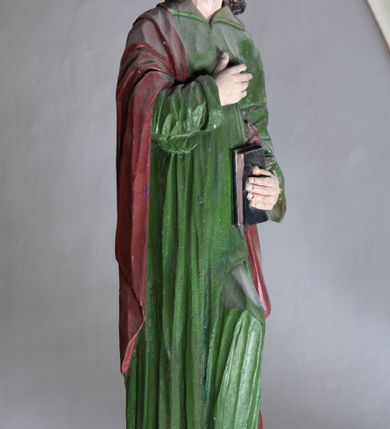 Zdjęcie nr 6: Rzeźba drewniana, pełnoplastyczna, polichromowana przedstawia stojącego na niewielkim postumencie św. Jana. Święty jest ukazany w pozycji stojącej, frontalnie, z lewą nogą ustawioną na niewielkim i wysuniętą do przodu, z ciałem lekko zwróconym w kierunku krzyża, z prawą ręką na piersi, z księgą w lewej dłoni. Jego głowa jest uniesiona, zwrócona ku Chrystusowi. Twarz owalna, oczy z opadającymi kącikami, nos prosty, usta małe. Włosy ciemne ułożone w pukle. Święty ubrany w długą, przepasaną w stanie zieloną suknię z kołnierzem oraz czerwono-brązowy płaszcz narzucony na prawe ramię i podtrzymywany ramieniem przy lewym boku. Fałdy szaty długie pionowe, układające się miękko.