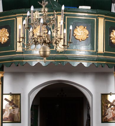 Zdjęcie nr 3: Chór muzyczny na zachodniej ścianie nawy, wsparty na dwóch słupach, ozdobionych od strony nawy dwoma kanelowanymi pilastrami o kapitelach kompozytowych. Jego parapet jest wklęsło-wypukły, z profilowanym cokołem, podzielony na kwatery kanelowanymi i złoconymi pilastrami. W kwaterach wypukłe pola kwadratowe o ćwierkolistych narożach ozdobione rzeźbionymi stylizowanymi rozetami. Parapet zwieńczony niewielkim gzymsem przełamanym na osi pilastrów. Pod listwą cokołu falisty fartuch. Struktura chóru muzycznego ciemnozielona. Pola płycin oliwkowo-ciemnozielone. Pilasty, rozety i profilowania są złocone. 
Znajdujący się na chórze prospekt wsparty na cokole z czterema kroksztynami, trzyosiowy, z osiami wydzielonymi kwadratowymi w podstawie filarkami. Oś środkowa podzielona na wie strefy: dolną z dwiema arkadkami z kostkowanym gzymsem i górną zamkniętą łukiem odcinkowym. Osie boczne zakończone gzymsem z kostkowaniem. W partii cokołowej bogato rzeźbiony motyw małżowinowo-chrząstkowy. 