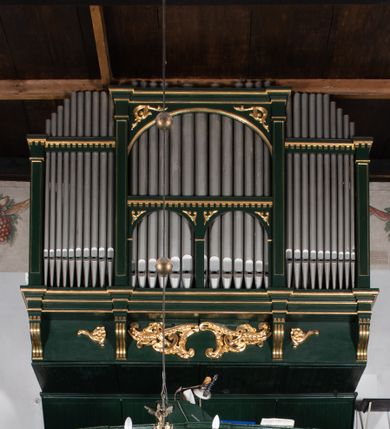 Zdjęcie nr 2: Chór muzyczny na zachodniej ścianie nawy, wsparty na dwóch słupach, ozdobionych od strony nawy dwoma kanelowanymi pilastrami o kapitelach kompozytowych. Jego parapet jest wklęsło-wypukły, z profilowanym cokołem, podzielony na kwatery kanelowanymi i złoconymi pilastrami. W kwaterach wypukłe pola kwadratowe o ćwierkolistych narożach ozdobione rzeźbionymi stylizowanymi rozetami. Parapet zwieńczony niewielkim gzymsem przełamanym na osi pilastrów. Pod listwą cokołu falisty fartuch. Struktura chóru muzycznego ciemnozielona. Pola płycin oliwkowo-ciemnozielone. Pilasty, rozety i profilowania są złocone. 
Znajdujący się na chórze prospekt wsparty na cokole z czterema kroksztynami, trzyosiowy, z osiami wydzielonymi kwadratowymi w podstawie filarkami. Oś środkowa podzielona na wie strefy: dolną z dwiema arkadkami z kostkowanym gzymsem i górną zamkniętą łukiem odcinkowym. Osie boczne zakończone gzymsem z kostkowaniem. W partii cokołowej bogato rzeźbiony motyw małżowinowo-chrząstkowy. 