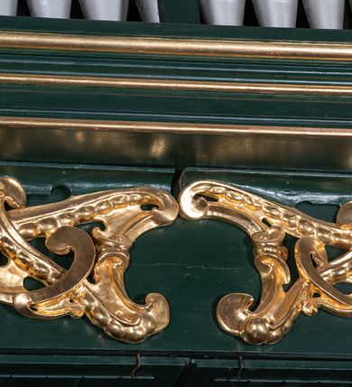 Zdjęcie nr 8: Chór muzyczny na zachodniej ścianie nawy, wsparty na dwóch słupach, ozdobionych od strony nawy dwoma kanelowanymi pilastrami o kapitelach kompozytowych. Jego parapet jest wklęsło-wypukły, z profilowanym cokołem, podzielony na kwatery kanelowanymi i złoconymi pilastrami. W kwaterach wypukłe pola kwadratowe o ćwierkolistych narożach ozdobione rzeźbionymi stylizowanymi rozetami. Parapet zwieńczony niewielkim gzymsem przełamanym na osi pilastrów. Pod listwą cokołu falisty fartuch. Struktura chóru muzycznego ciemnozielona. Pola płycin oliwkowo-ciemnozielone. Pilasty, rozety i profilowania są złocone. 
Znajdujący się na chórze prospekt wsparty na cokole z czterema kroksztynami, trzyosiowy, z osiami wydzielonymi kwadratowymi w podstawie filarkami. Oś środkowa podzielona na wie strefy: dolną z dwiema arkadkami z kostkowanym gzymsem i górną zamkniętą łukiem odcinkowym. Osie boczne zakończone gzymsem z kostkowaniem. W partii cokołowej bogato rzeźbiony motyw małżowinowo-chrząstkowy. 