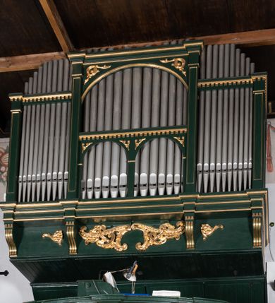 Zdjęcie nr 7: Chór muzyczny na zachodniej ścianie nawy, wsparty na dwóch słupach, ozdobionych od strony nawy dwoma kanelowanymi pilastrami o kapitelach kompozytowych. Jego parapet jest wklęsło-wypukły, z profilowanym cokołem, podzielony na kwatery kanelowanymi i złoconymi pilastrami. W kwaterach wypukłe pola kwadratowe o ćwierkolistych narożach ozdobione rzeźbionymi stylizowanymi rozetami. Parapet zwieńczony niewielkim gzymsem przełamanym na osi pilastrów. Pod listwą cokołu falisty fartuch. Struktura chóru muzycznego ciemnozielona. Pola płycin oliwkowo-ciemnozielone. Pilasty, rozety i profilowania są złocone. 
Znajdujący się na chórze prospekt wsparty na cokole z czterema kroksztynami, trzyosiowy, z osiami wydzielonymi kwadratowymi w podstawie filarkami. Oś środkowa podzielona na wie strefy: dolną z dwiema arkadkami z kostkowanym gzymsem i górną zamkniętą łukiem odcinkowym. Osie boczne zakończone gzymsem z kostkowaniem. W partii cokołowej bogato rzeźbiony motyw małżowinowo-chrząstkowy. 