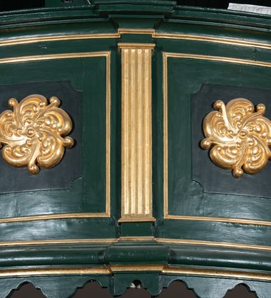 Zdjęcie nr 11: Chór muzyczny na zachodniej ścianie nawy, wsparty na dwóch słupach, ozdobionych od strony nawy dwoma kanelowanymi pilastrami o kapitelach kompozytowych. Jego parapet jest wklęsło-wypukły, z profilowanym cokołem, podzielony na kwatery kanelowanymi i złoconymi pilastrami. W kwaterach wypukłe pola kwadratowe o ćwierkolistych narożach ozdobione rzeźbionymi stylizowanymi rozetami. Parapet zwieńczony niewielkim gzymsem przełamanym na osi pilastrów. Pod listwą cokołu falisty fartuch. Struktura chóru muzycznego ciemnozielona. Pola płycin oliwkowo-ciemnozielone. Pilasty, rozety i profilowania są złocone. 
Znajdujący się na chórze prospekt wsparty na cokole z czterema kroksztynami, trzyosiowy, z osiami wydzielonymi kwadratowymi w podstawie filarkami. Oś środkowa podzielona na wie strefy: dolną z dwiema arkadkami z kostkowanym gzymsem i górną zamkniętą łukiem odcinkowym. Osie boczne zakończone gzymsem z kostkowaniem. W partii cokołowej bogato rzeźbiony motyw małżowinowo-chrząstkowy. 