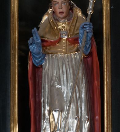 Zdjęcie nr 18: Ołtarz architektoniczny, na wysokim cokole, jednokondygnacyjny, trójosiowy, ze zwieńczeniem; osie wyznaczone umieszczonymi na wysokich cokołach kolumnami o kapitelach kompozytowych, podtrzymującymi występujące nad podporami uproszczone belkowanie i gzyms, ponad nimi trójkątny, przerywany przyczółek. W strefie dolnej, w osiach skrajnych, po bokach mensy bramki zamknięte półkoliście, służące do obejścia ołtarza. Mensa prostopadłościenna, o profilowanym obramieniu antependium i z profilowanymi prostokątnymi płycinami na bokach. Powyżej, w pierwszej kondygnacji, w osiach skrajnych nisze zamknięte łukiem półkolistym z konchami muszlowymi, w osi środkowej prostokątna wnęka na obraz ołtarzowy. Płyciny na cokołach, powyżej półkolistych wnęk oraz na predelli ażurowe, w kształcie prostokąta z uszakami. Zwieńczenie jednoosiowe, flankowane kolumienkami o kapitelach kompozytowych, z występującym nad podporami belkowaniem i gzymsem oraz półkolistym przerywanym przyczółkiem. W polu środkowym owalna profilowana nisza na obraz, ponad którą w szczycie ołtarza gloria promienista. Nastawa flankowana uszakami w z motywów ornamentu małżowinowo-chrząstkowego. Belkowanie, profilowane, prostokątne pole na obraz, predella oraz płyciny na cokołach i powyżej półkolistych wnęk, wypełnione ornamentem małżowinowo-chrząstkowym. Powyżej bramek w części cokołowej podwieszone girlandy. W zwieńczeniu małżowinowo-chrząstkowe uszaki oraz płyciny wypełnione ornamentem małżowinowo-chrząstkowym. W narożach stylizowane liście. Profilowana wnęka na obraz w zwieńczeniu  wypełniona lilijkami. Kolumny, gzymsy i profilowania otworów złocone. Gloria promienista z puttami oraz Okiem Opatrzności na tle trójkąta równobocznego. Antepedium ozdobione romboidalną siatką, w narożach wstęga regencyjna przechodząca w akant. Pośrodku litery IHS w glorii promienistej. W płycinach na cokołach i powyżej wnęk główki puttów. W niszach rzeźby św. Wojciecha i św. Stanisława. W centralnym polu obraz z przedstawieniem św. Grzegorza Wielkiego, w zwieńczeniu Wniebowzięcie Najświętszej Marii Panny. Na przerywanym przyczółku nastawy rzeźby aniołów. Rzeźba anioła po lewej stronie, pełna, całopostaciowa. Anioł ukazany w pozycji półleżącej, w trzech czwartych, z lewą nogą wysuniętą i wzniesioną głową. Ręce ugięte w łokciach i uniesione. Twarz pociągła, włosy ciemne, kręcone, sięgające do ramion i odsłaniające uszy. Anioł odziany jest w długą, złotą suknię, z podwiniętymi rękawami i odsłaniającą lewą nogę. Fałdy głęboko rzeźbione, na kształt litery V i pionowych rurek.Rzeźba anioła po prawej, pełna, całopostaciowa. Anioł ukazany w pozycji półleżącej, w trzech czwartych, z lewą nogą wysuniętą i wzniesioną głową. Lewa ręka ugięta w łokciu i ułożona na piersi, prawa wyprostowana. Twarz pociągła, włosy ciemne, kręcone, sięgające do ramion i odsłaniające uszy. Anioł ubrany w długą, złotą suknię, z podwiniętymi rękawami i odsłaniającą lewą nogę. Fałdy głęboko rzeźbione, na kształt litery V i pionowych rurek.