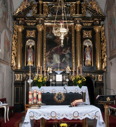 Zdjęcie nr 4: Ołtarz architektoniczny, na wysokim cokole, jednokondygnacyjny, trójosiowy, ze zwieńczeniem; osie wyznaczone umieszczonymi na wysokich cokołach kolumnami o kapitelach kompozytowych, podtrzymującymi występujące nad podporami uproszczone belkowanie i gzyms, ponad nimi trójkątny, przerywany przyczółek. W strefie dolnej, w osiach skrajnych, po bokach mensy bramki zamknięte półkoliście, służące do obejścia ołtarza. Mensa prostopadłościenna, o profilowanym obramieniu antependium i z profilowanymi prostokątnymi płycinami na bokach. Powyżej, w pierwszej kondygnacji, w osiach skrajnych nisze zamknięte łukiem półkolistym z konchami muszlowymi, w osi środkowej prostokątna wnęka na obraz ołtarzowy. Płyciny na cokołach, powyżej półkolistych wnęk oraz na predelli ażurowe, w kształcie prostokąta z uszakami. Zwieńczenie jednoosiowe, flankowane kolumienkami o kapitelach kompozytowych, z występującym nad podporami belkowaniem i gzymsem oraz półkolistym przerywanym przyczółkiem. W polu środkowym owalna profilowana nisza na obraz, ponad którą w szczycie ołtarza gloria promienista. Nastawa flankowana uszakami w z motywów ornamentu małżowinowo-chrząstkowego. Belkowanie, profilowane, prostokątne pole na obraz, predella oraz płyciny na cokołach i powyżej półkolistych wnęk, wypełnione ornamentem małżowinowo-chrząstkowym. Powyżej bramek w części cokołowej podwieszone girlandy. W zwieńczeniu małżowinowo-chrząstkowe uszaki oraz płyciny wypełnione ornamentem małżowinowo-chrząstkowym. W narożach stylizowane liście. Profilowana wnęka na obraz w zwieńczeniu  wypełniona lilijkami. Kolumny, gzymsy i profilowania otworów złocone. Gloria promienista z puttami oraz Okiem Opatrzności na tle trójkąta równobocznego. Antepedium ozdobione romboidalną siatką, w narożach wstęga regencyjna przechodząca w akant. Pośrodku litery IHS w glorii promienistej. W płycinach na cokołach i powyżej wnęk główki puttów. W niszach rzeźby św. Wojciecha i św. Stanisława. W centralnym polu obraz z przedstawieniem św. Grzegorza Wielkiego, w zwieńczeniu Wniebowzięcie Najświętszej Marii Panny. Na przerywanym przyczółku nastawy rzeźby aniołów. Rzeźba anioła po lewej stronie, pełna, całopostaciowa. Anioł ukazany w pozycji półleżącej, w trzech czwartych, z lewą nogą wysuniętą i wzniesioną głową. Ręce ugięte w łokciach i uniesione. Twarz pociągła, włosy ciemne, kręcone, sięgające do ramion i odsłaniające uszy. Anioł odziany jest w długą, złotą suknię, z podwiniętymi rękawami i odsłaniającą lewą nogę. Fałdy głęboko rzeźbione, na kształt litery V i pionowych rurek.Rzeźba anioła po prawej, pełna, całopostaciowa. Anioł ukazany w pozycji półleżącej, w trzech czwartych, z lewą nogą wysuniętą i wzniesioną głową. Lewa ręka ugięta w łokciu i ułożona na piersi, prawa wyprostowana. Twarz pociągła, włosy ciemne, kręcone, sięgające do ramion i odsłaniające uszy. Anioł ubrany w długą, złotą suknię, z podwiniętymi rękawami i odsłaniającą lewą nogę. Fałdy głęboko rzeźbione, na kształt litery V i pionowych rurek.