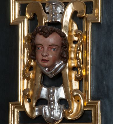 Zdjęcie nr 33: Ołtarz architektoniczny, na wysokim cokole, jednokondygnacyjny, trójosiowy, ze zwieńczeniem; osie wyznaczone umieszczonymi na wysokich cokołach kolumnami o kapitelach kompozytowych, podtrzymującymi występujące nad podporami uproszczone belkowanie i gzyms, ponad nimi trójkątny, przerywany przyczółek. W strefie dolnej, w osiach skrajnych, po bokach mensy bramki zamknięte półkoliście, służące do obejścia ołtarza. Mensa prostopadłościenna, o profilowanym obramieniu antependium i z profilowanymi prostokątnymi płycinami na bokach. Powyżej, w pierwszej kondygnacji, w osiach skrajnych nisze zamknięte łukiem półkolistym z konchami muszlowymi, w osi środkowej prostokątna wnęka na obraz ołtarzowy. Płyciny na cokołach, powyżej półkolistych wnęk oraz na predelli ażurowe, w kształcie prostokąta z uszakami. Zwieńczenie jednoosiowe, flankowane kolumienkami o kapitelach kompozytowych, z występującym nad podporami belkowaniem i gzymsem oraz półkolistym przerywanym przyczółkiem. W polu środkowym owalna profilowana nisza na obraz, ponad którą w szczycie ołtarza gloria promienista. Nastawa flankowana uszakami w z motywów ornamentu małżowinowo-chrząstkowego. Belkowanie, profilowane, prostokątne pole na obraz, predella oraz płyciny na cokołach i powyżej półkolistych wnęk, wypełnione ornamentem małżowinowo-chrząstkowym. Powyżej bramek w części cokołowej podwieszone girlandy. W zwieńczeniu małżowinowo-chrząstkowe uszaki oraz płyciny wypełnione ornamentem małżowinowo-chrząstkowym. W narożach stylizowane liście. Profilowana wnęka na obraz w zwieńczeniu  wypełniona lilijkami. Kolumny, gzymsy i profilowania otworów złocone. Gloria promienista z puttami oraz Okiem Opatrzności na tle trójkąta równobocznego. Antepedium ozdobione romboidalną siatką, w narożach wstęga regencyjna przechodząca w akant. Pośrodku litery IHS w glorii promienistej. W płycinach na cokołach i powyżej wnęk główki puttów. W niszach rzeźby św. Wojciecha i św. Stanisława. W centralnym polu obraz z przedstawieniem św. Grzegorza Wielkiego, w zwieńczeniu Wniebowzięcie Najświętszej Marii Panny. Na przerywanym przyczółku nastawy rzeźby aniołów. Rzeźba anioła po lewej stronie, pełna, całopostaciowa. Anioł ukazany w pozycji półleżącej, w trzech czwartych, z lewą nogą wysuniętą i wzniesioną głową. Ręce ugięte w łokciach i uniesione. Twarz pociągła, włosy ciemne, kręcone, sięgające do ramion i odsłaniające uszy. Anioł odziany jest w długą, złotą suknię, z podwiniętymi rękawami i odsłaniającą lewą nogę. Fałdy głęboko rzeźbione, na kształt litery V i pionowych rurek.Rzeźba anioła po prawej, pełna, całopostaciowa. Anioł ukazany w pozycji półleżącej, w trzech czwartych, z lewą nogą wysuniętą i wzniesioną głową. Lewa ręka ugięta w łokciu i ułożona na piersi, prawa wyprostowana. Twarz pociągła, włosy ciemne, kręcone, sięgające do ramion i odsłaniające uszy. Anioł ubrany w długą, złotą suknię, z podwiniętymi rękawami i odsłaniającą lewą nogę. Fałdy głęboko rzeźbione, na kształt litery V i pionowych rurek.