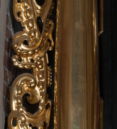 Zdjęcie nr 38: Ołtarz architektoniczny, na wysokim cokole, jednokondygnacyjny, trójosiowy, ze zwieńczeniem; osie wyznaczone umieszczonymi na wysokich cokołach kolumnami o kapitelach kompozytowych, podtrzymującymi występujące nad podporami uproszczone belkowanie i gzyms, ponad nimi trójkątny, przerywany przyczółek. W strefie dolnej, w osiach skrajnych, po bokach mensy bramki zamknięte półkoliście, służące do obejścia ołtarza. Mensa prostopadłościenna, o profilowanym obramieniu antependium i z profilowanymi prostokątnymi płycinami na bokach. Powyżej, w pierwszej kondygnacji, w osiach skrajnych nisze zamknięte łukiem półkolistym z konchami muszlowymi, w osi środkowej prostokątna wnęka na obraz ołtarzowy. Płyciny na cokołach, powyżej półkolistych wnęk oraz na predelli ażurowe, w kształcie prostokąta z uszakami. Zwieńczenie jednoosiowe, flankowane kolumienkami o kapitelach kompozytowych, z występującym nad podporami belkowaniem i gzymsem oraz półkolistym przerywanym przyczółkiem. W polu środkowym owalna profilowana nisza na obraz, ponad którą w szczycie ołtarza gloria promienista. Nastawa flankowana uszakami w z motywów ornamentu małżowinowo-chrząstkowego. Belkowanie, profilowane, prostokątne pole na obraz, predella oraz płyciny na cokołach i powyżej półkolistych wnęk, wypełnione ornamentem małżowinowo-chrząstkowym. Powyżej bramek w części cokołowej podwieszone girlandy. W zwieńczeniu małżowinowo-chrząstkowe uszaki oraz płyciny wypełnione ornamentem małżowinowo-chrząstkowym. W narożach stylizowane liście. Profilowana wnęka na obraz w zwieńczeniu  wypełniona lilijkami. Kolumny, gzymsy i profilowania otworów złocone. Gloria promienista z puttami oraz Okiem Opatrzności na tle trójkąta równobocznego. Antepedium ozdobione romboidalną siatką, w narożach wstęga regencyjna przechodząca w akant. Pośrodku litery IHS w glorii promienistej. W płycinach na cokołach i powyżej wnęk główki puttów. W niszach rzeźby św. Wojciecha i św. Stanisława. W centralnym polu obraz z przedstawieniem św. Grzegorza Wielkiego, w zwieńczeniu Wniebowzięcie Najświętszej Marii Panny. Na przerywanym przyczółku nastawy rzeźby aniołów. Rzeźba anioła po lewej stronie, pełna, całopostaciowa. Anioł ukazany w pozycji półleżącej, w trzech czwartych, z lewą nogą wysuniętą i wzniesioną głową. Ręce ugięte w łokciach i uniesione. Twarz pociągła, włosy ciemne, kręcone, sięgające do ramion i odsłaniające uszy. Anioł odziany jest w długą, złotą suknię, z podwiniętymi rękawami i odsłaniającą lewą nogę. Fałdy głęboko rzeźbione, na kształt litery V i pionowych rurek.Rzeźba anioła po prawej, pełna, całopostaciowa. Anioł ukazany w pozycji półleżącej, w trzech czwartych, z lewą nogą wysuniętą i wzniesioną głową. Lewa ręka ugięta w łokciu i ułożona na piersi, prawa wyprostowana. Twarz pociągła, włosy ciemne, kręcone, sięgające do ramion i odsłaniające uszy. Anioł ubrany w długą, złotą suknię, z podwiniętymi rękawami i odsłaniającą lewą nogę. Fałdy głęboko rzeźbione, na kształt litery V i pionowych rurek.